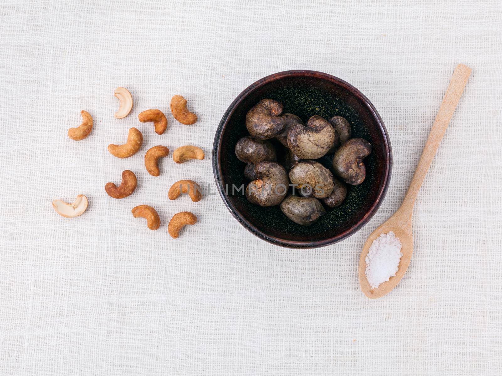 Raw cashews nut in the bowl with salt on white table. by kerdkanno