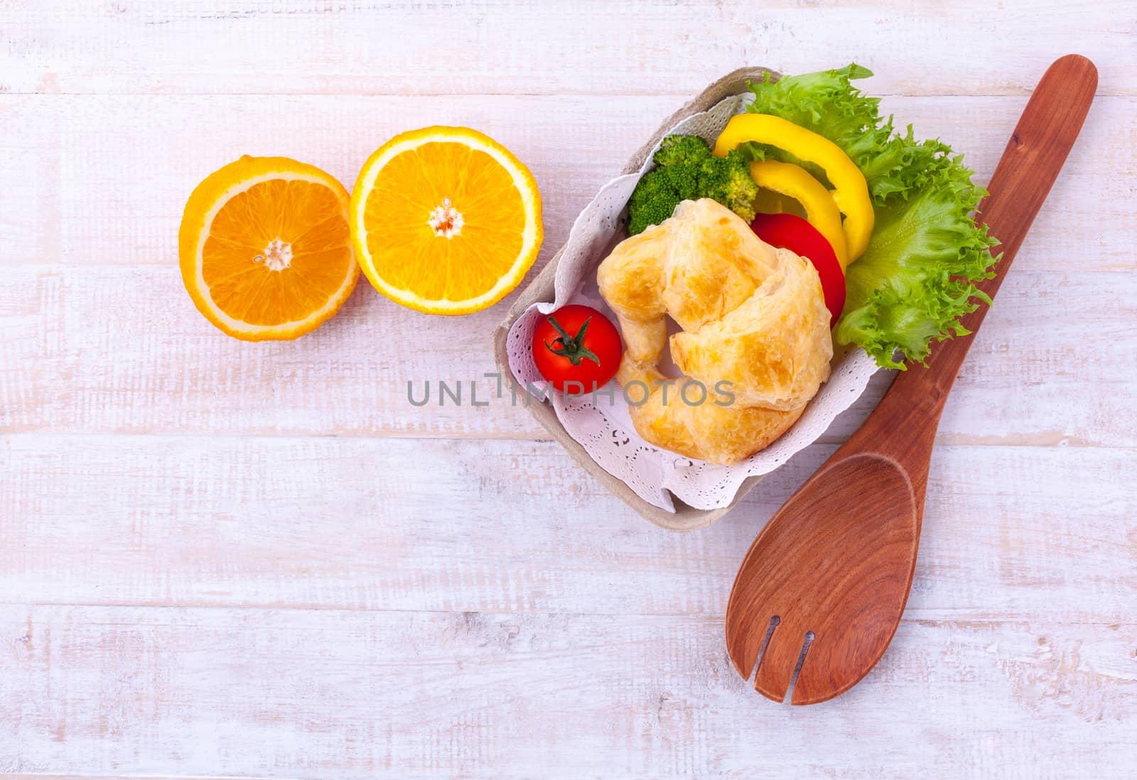 Clean food breakfast croissant and salad on wooden table.