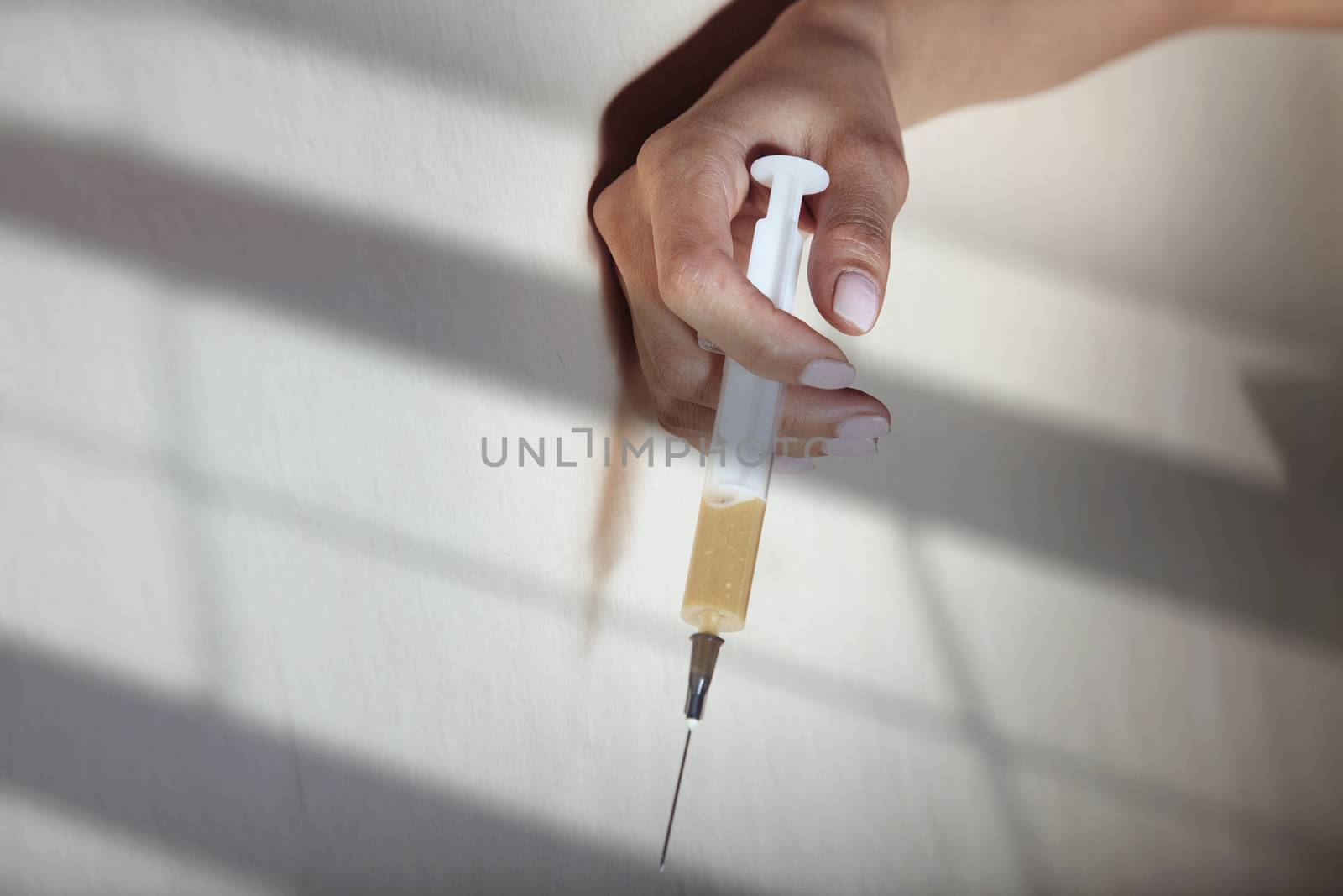 Hand of the narcotist indoors holding syringe with heroin