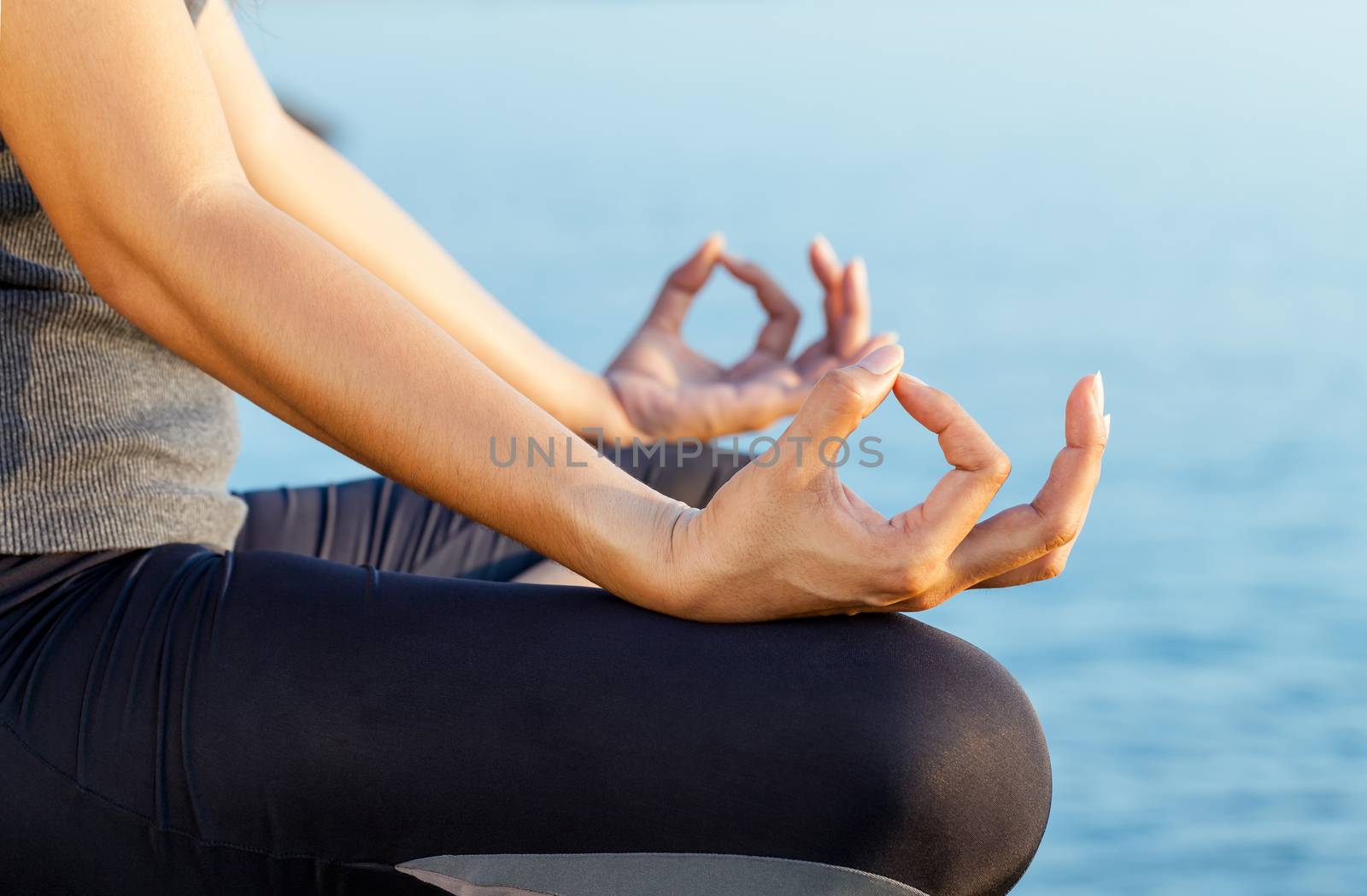 The woman meditating in a yoga pose on the tropical beach.