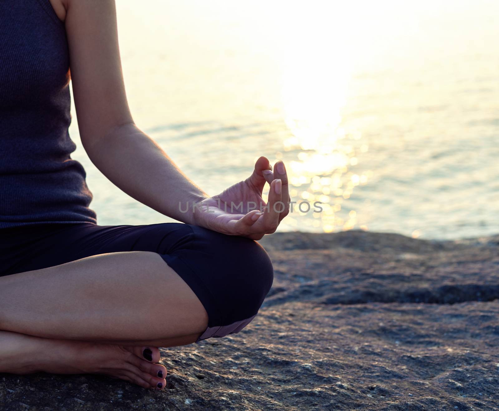 The woman meditating in a yoga pose on the tropical beach. by kerdkanno