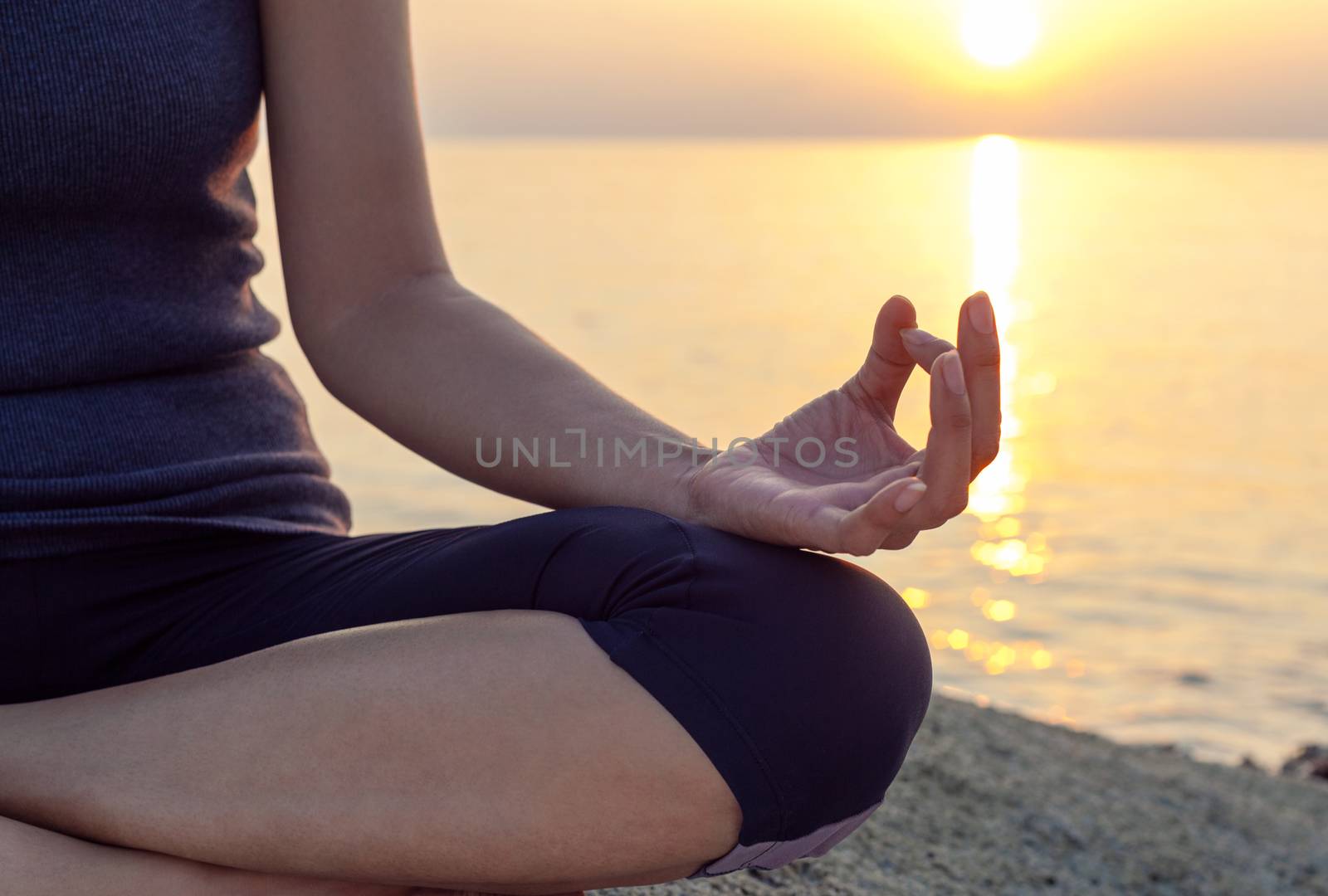 The woman meditating in a yoga pose on the tropical beach. by kerdkanno