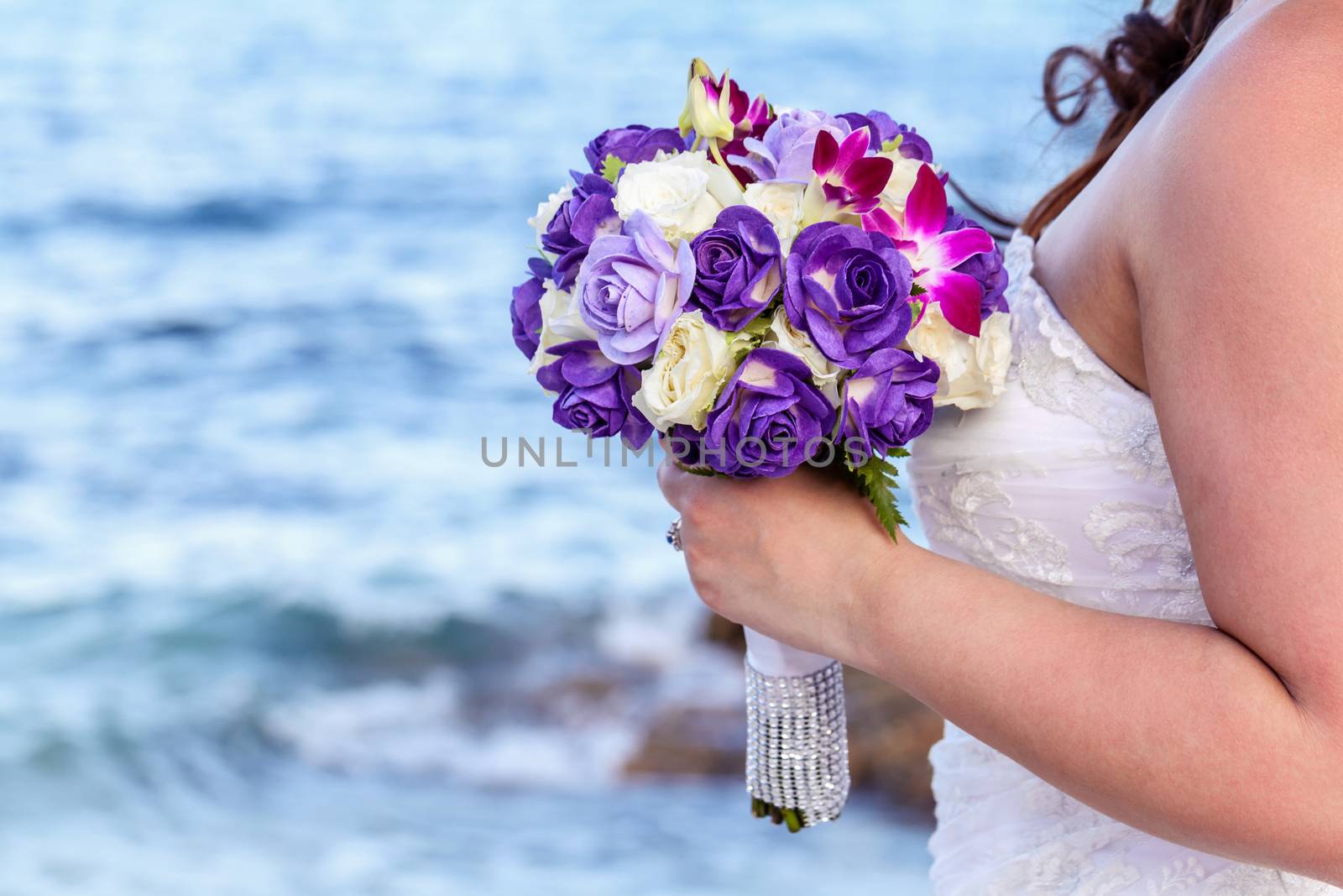 The bride holding wedding bouquet at tropical beach.