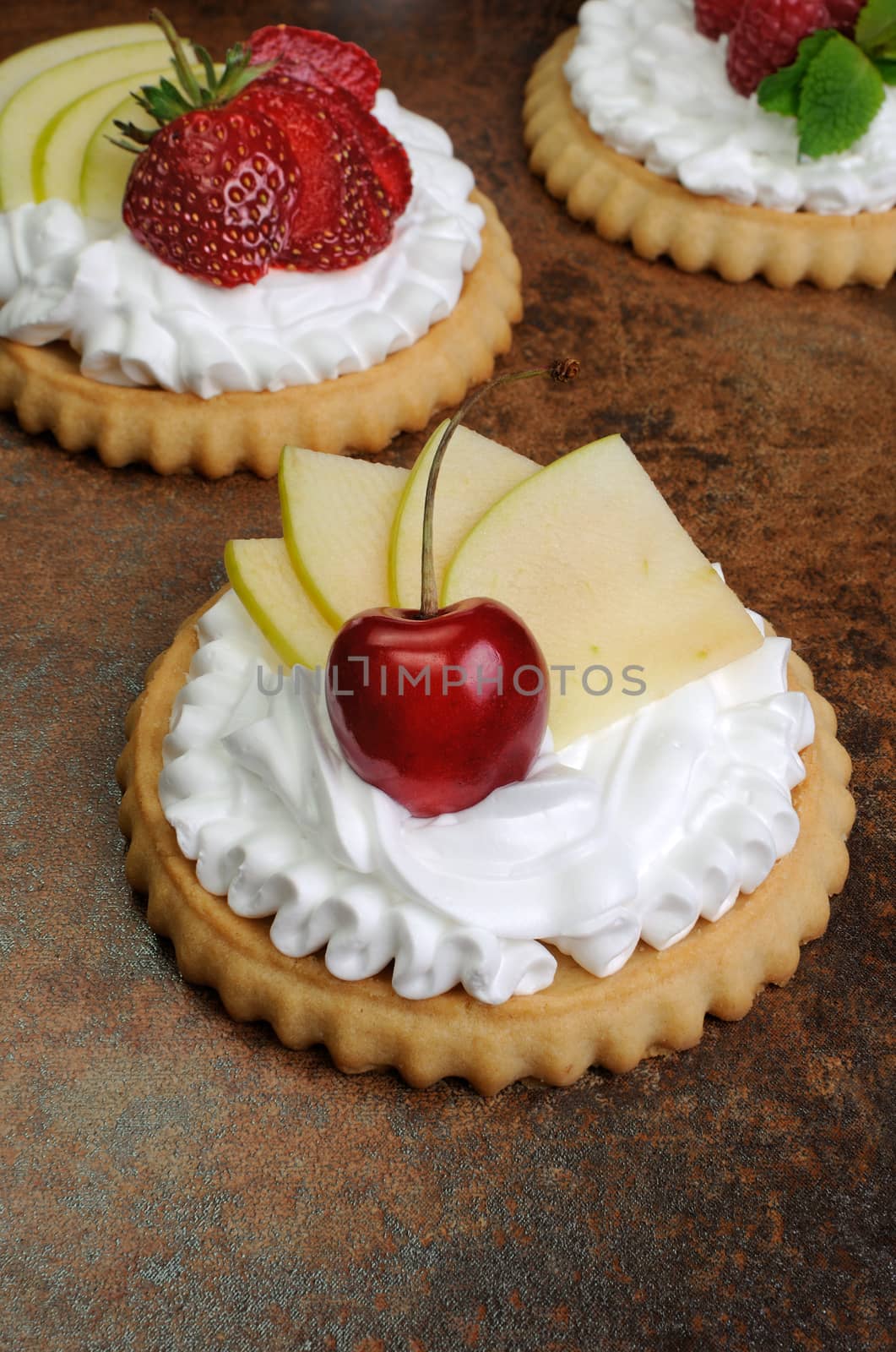 Tartlets with whipped cream on cherry and apple