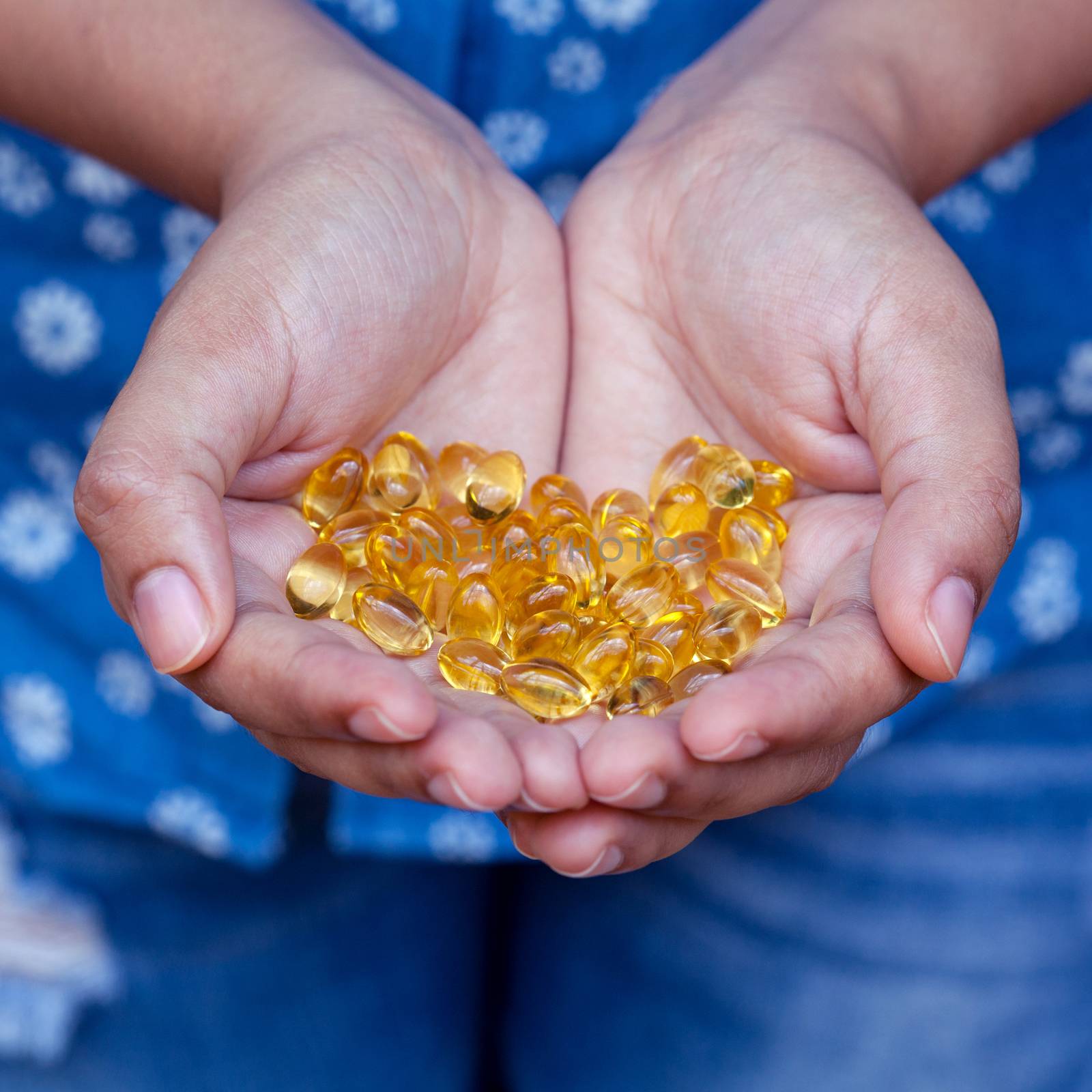 Pills of fish oil holding by young girl. by kerdkanno