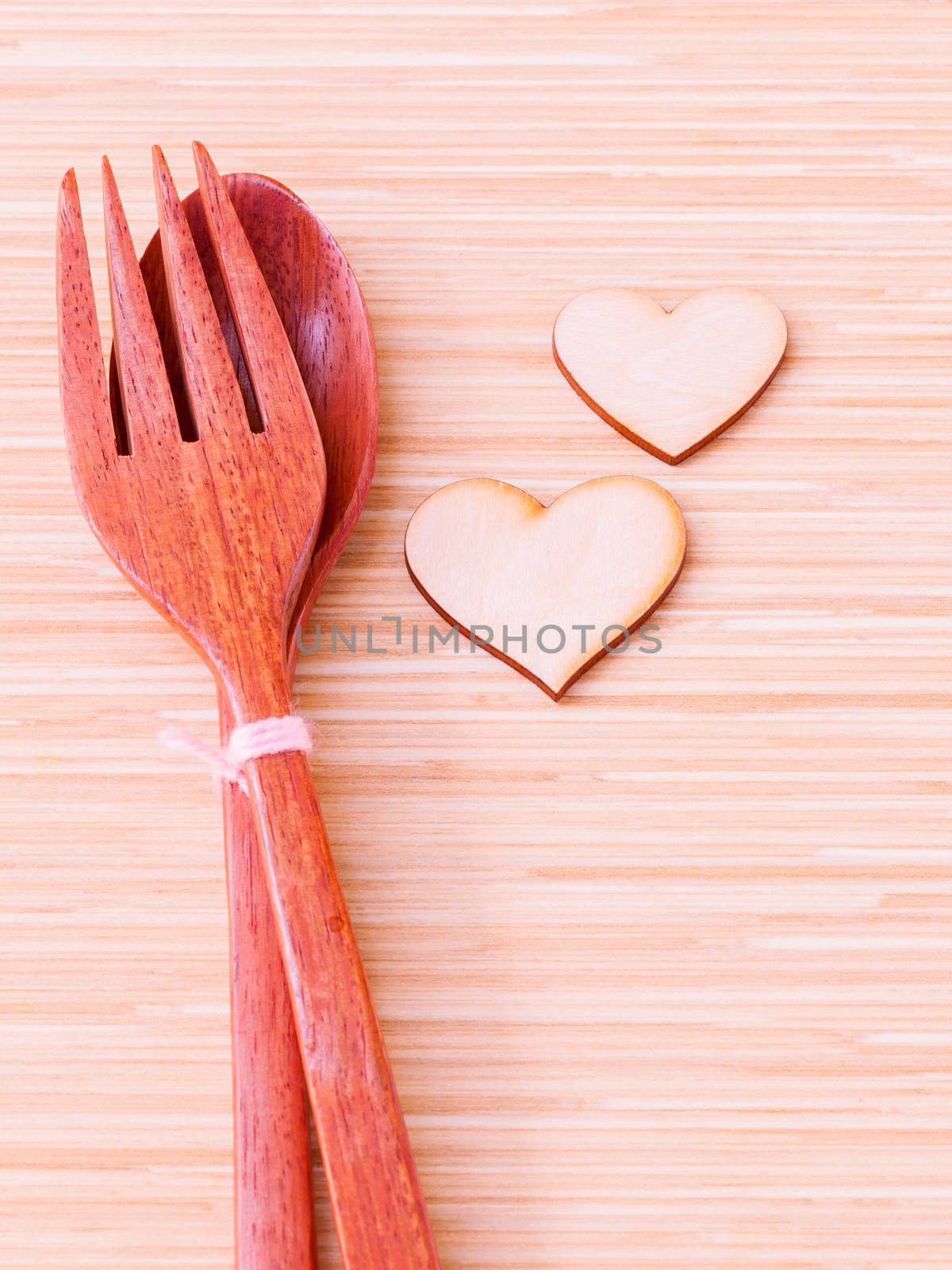 Wooden spoon and fork with wooden shape of heart . - Concept for wedding menu.