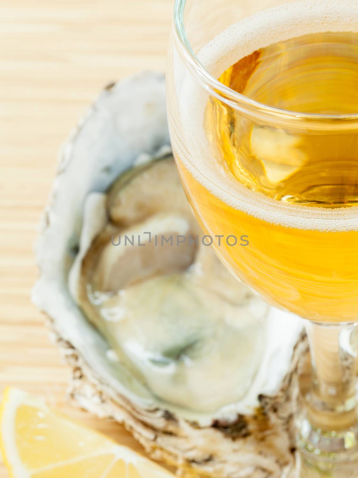 Fresh oysters with lemon and a glass of wine on a wooden table . by kerdkanno