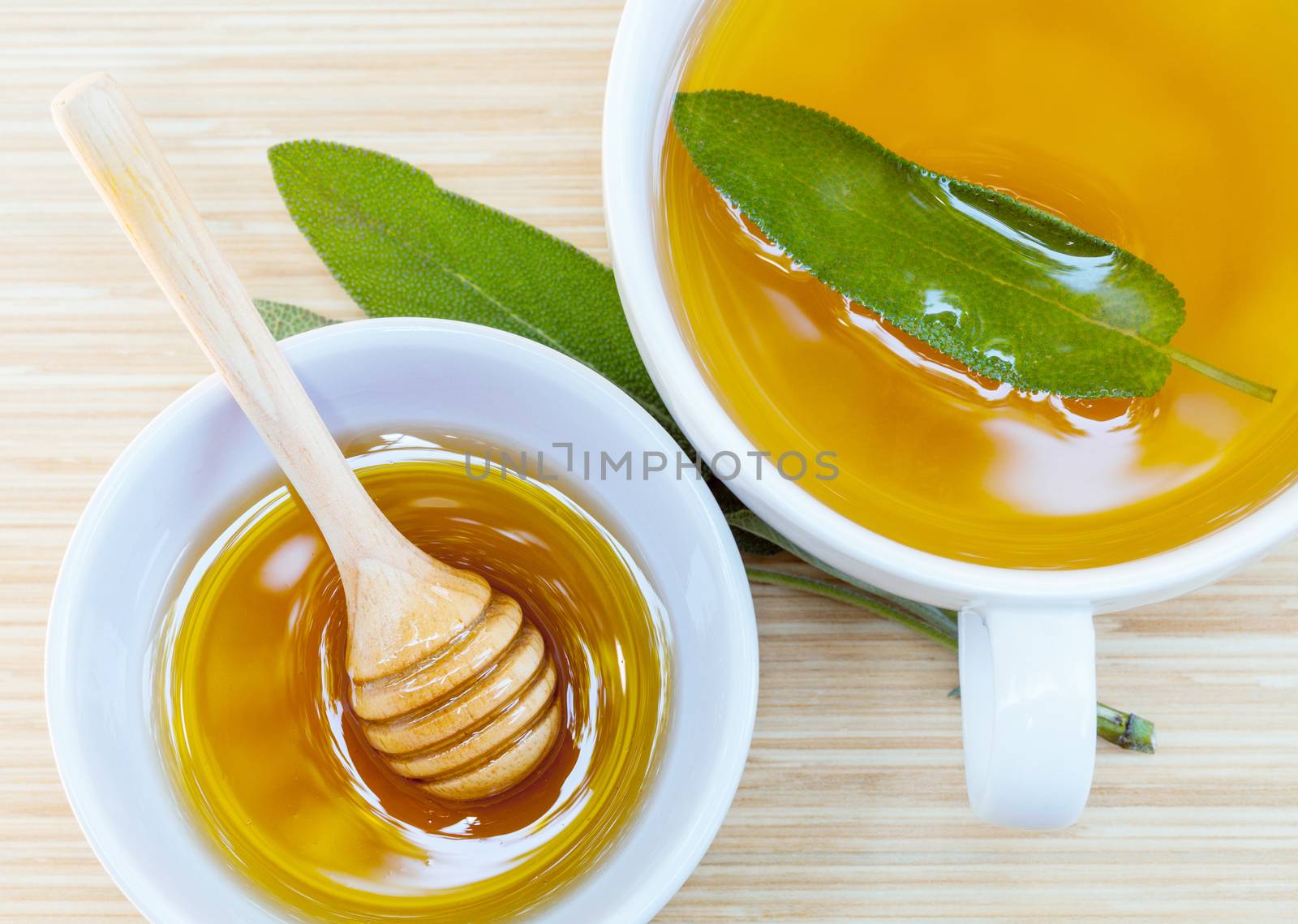 A cup of sage tea with fresh sage and honey.