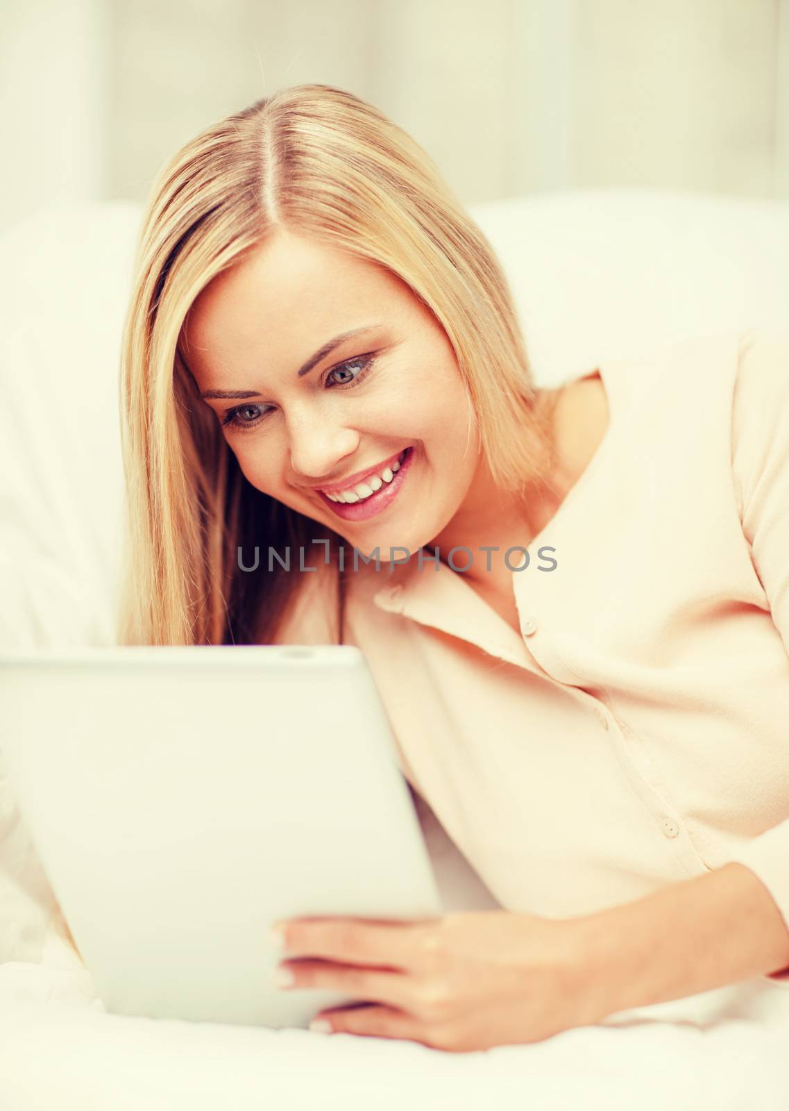 leisure and education concept - smiling woman lying on the couch with tablet pc