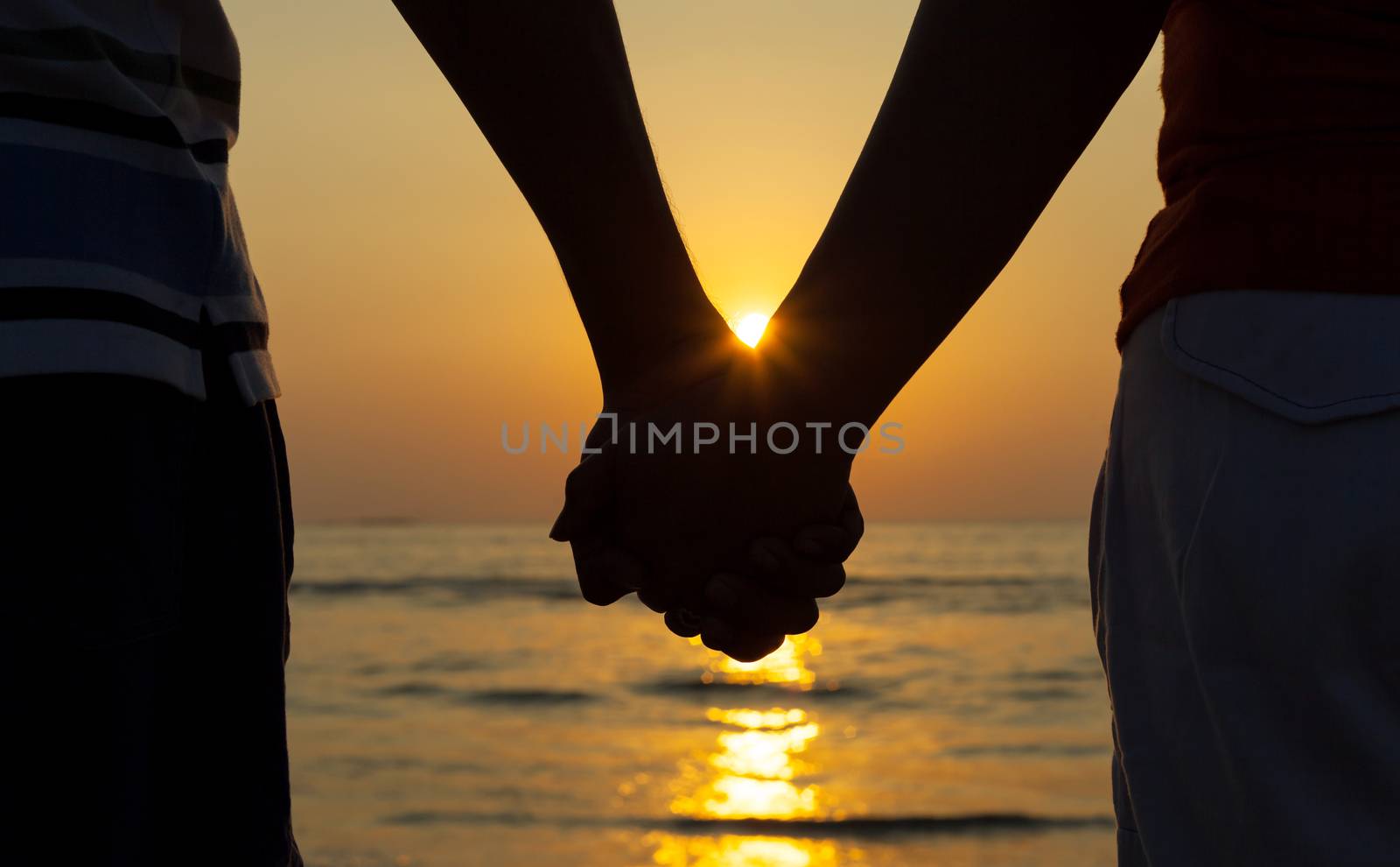 Silhouettes couples holding hands on sunset.