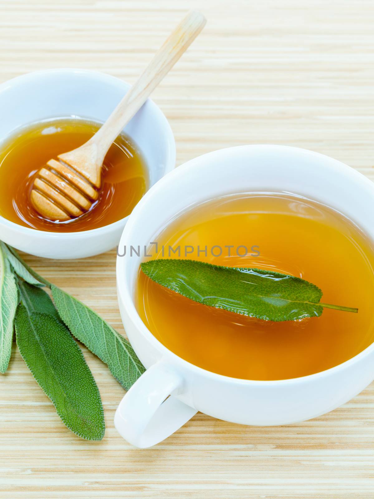 A cup of sage tea with fresh sage and honey.