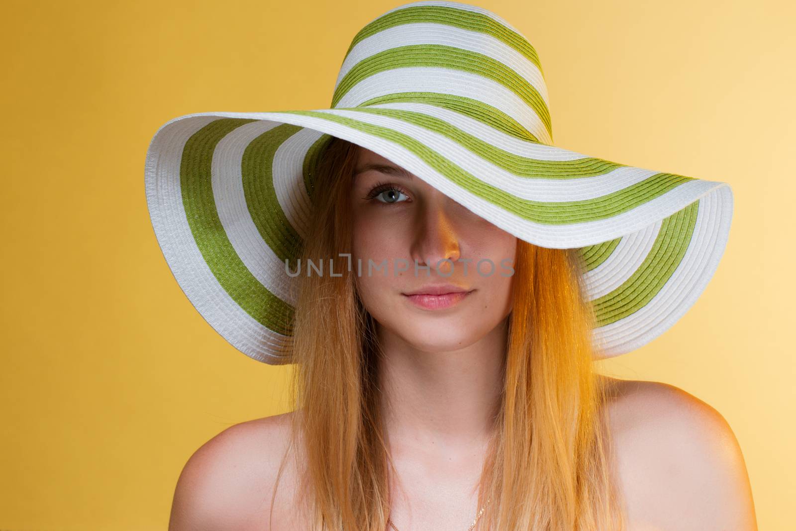 young pretty girl with a hat on her head. Yellow background. horizontal