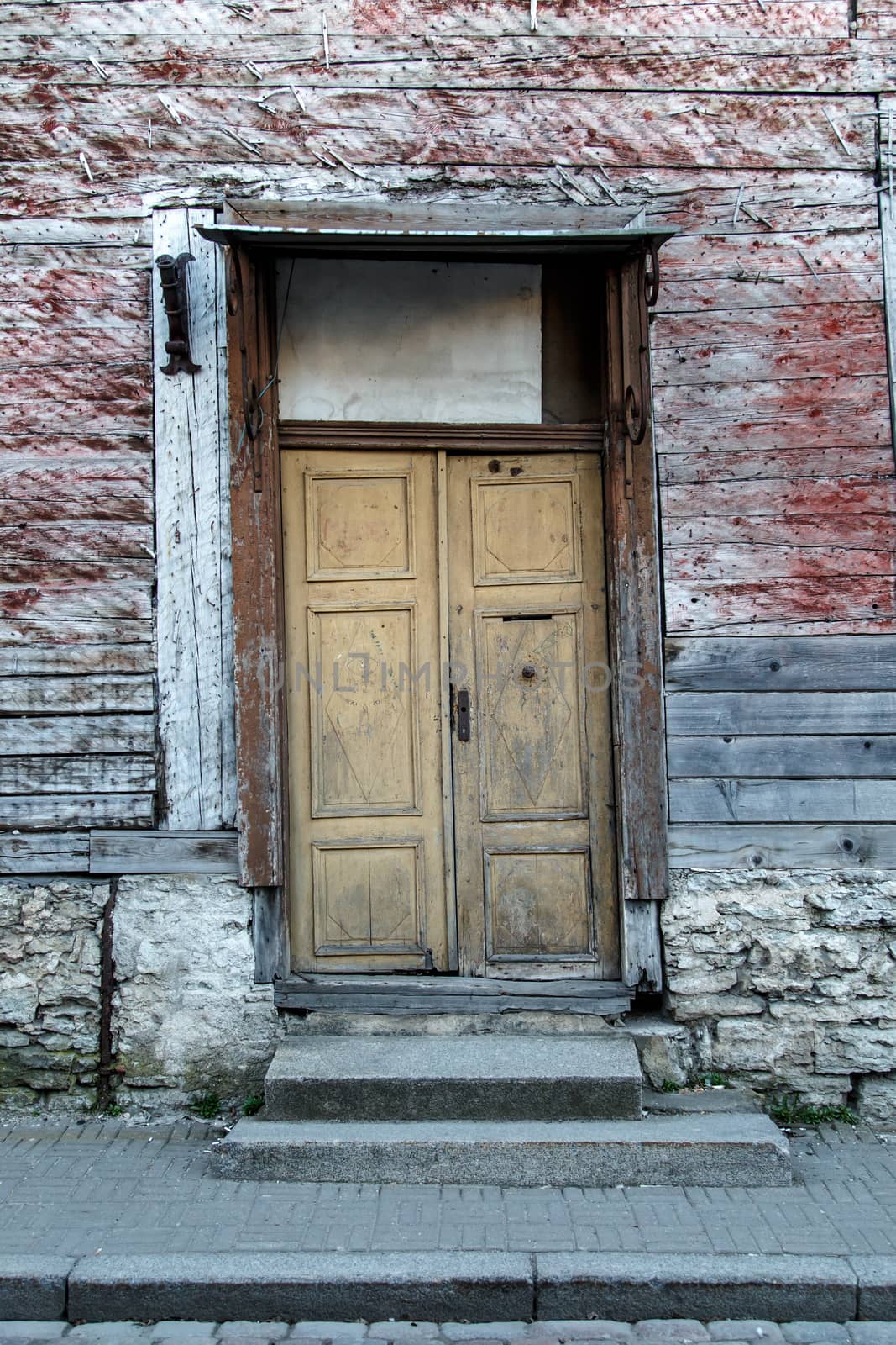 Close up view of yellow wooden door of the old red or brown wooden building.