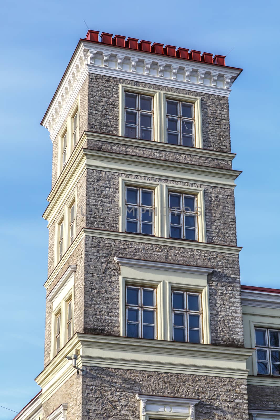 Close up view of stonewall building with four floors, on blue sky background.