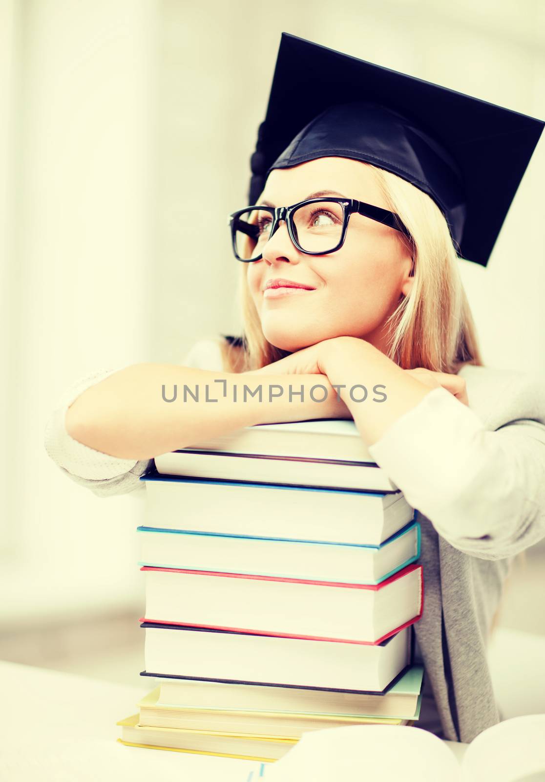 business and education concept - happy student in graduation cap with stack of books