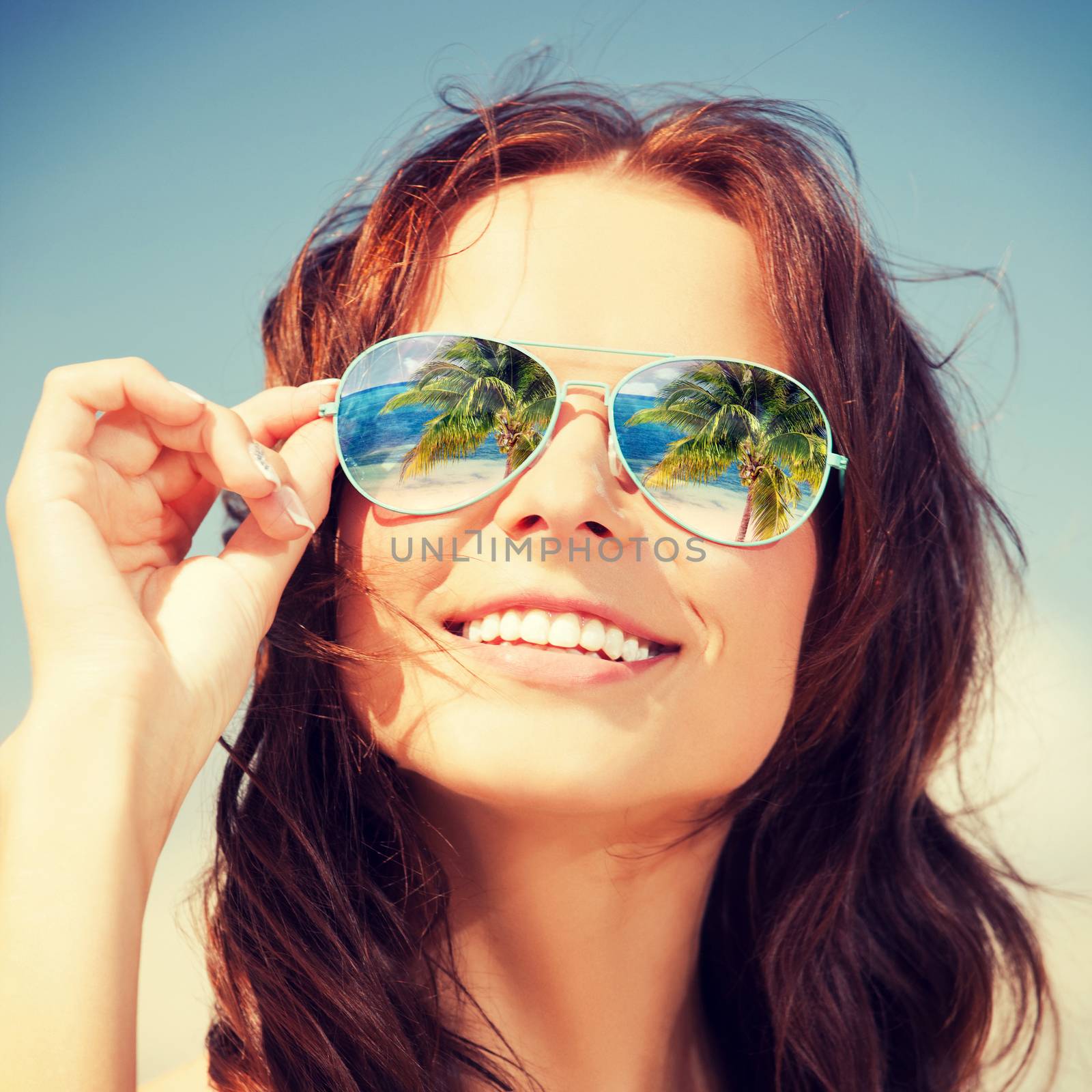 holidays, travel, vacation and happiness concept - beautiful woman in sunglasses with beach reflection