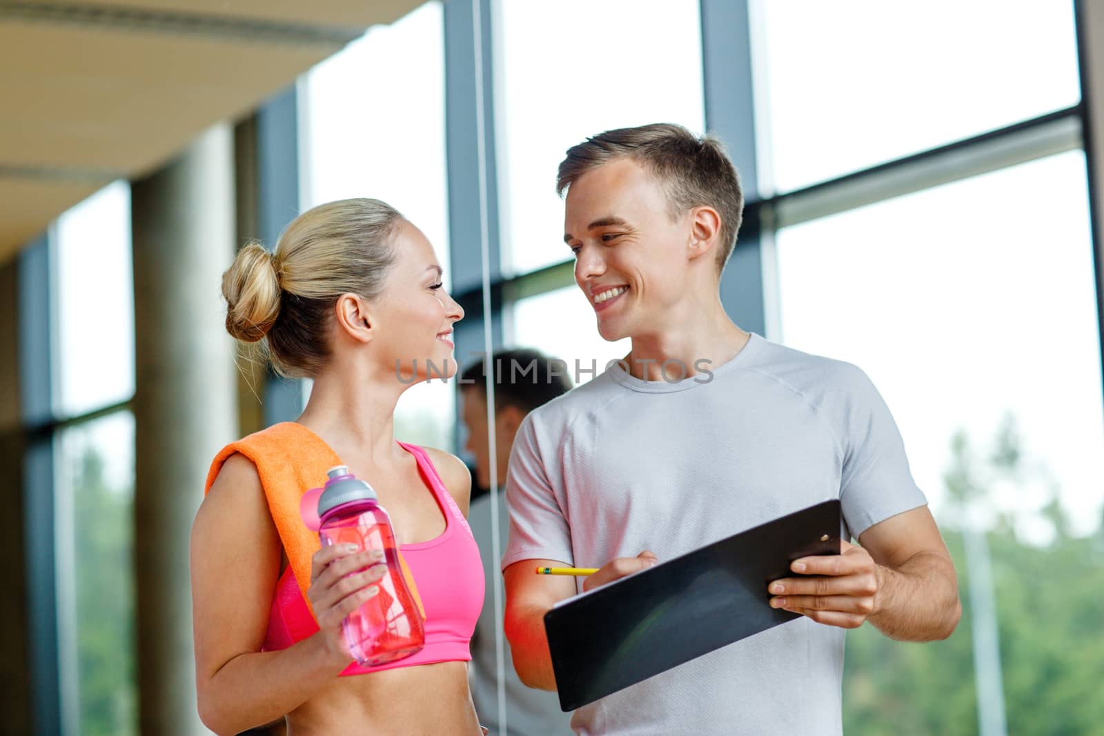 fitness, sport, exercising and diet concept - smiling young woman with personal trainer after training in gym