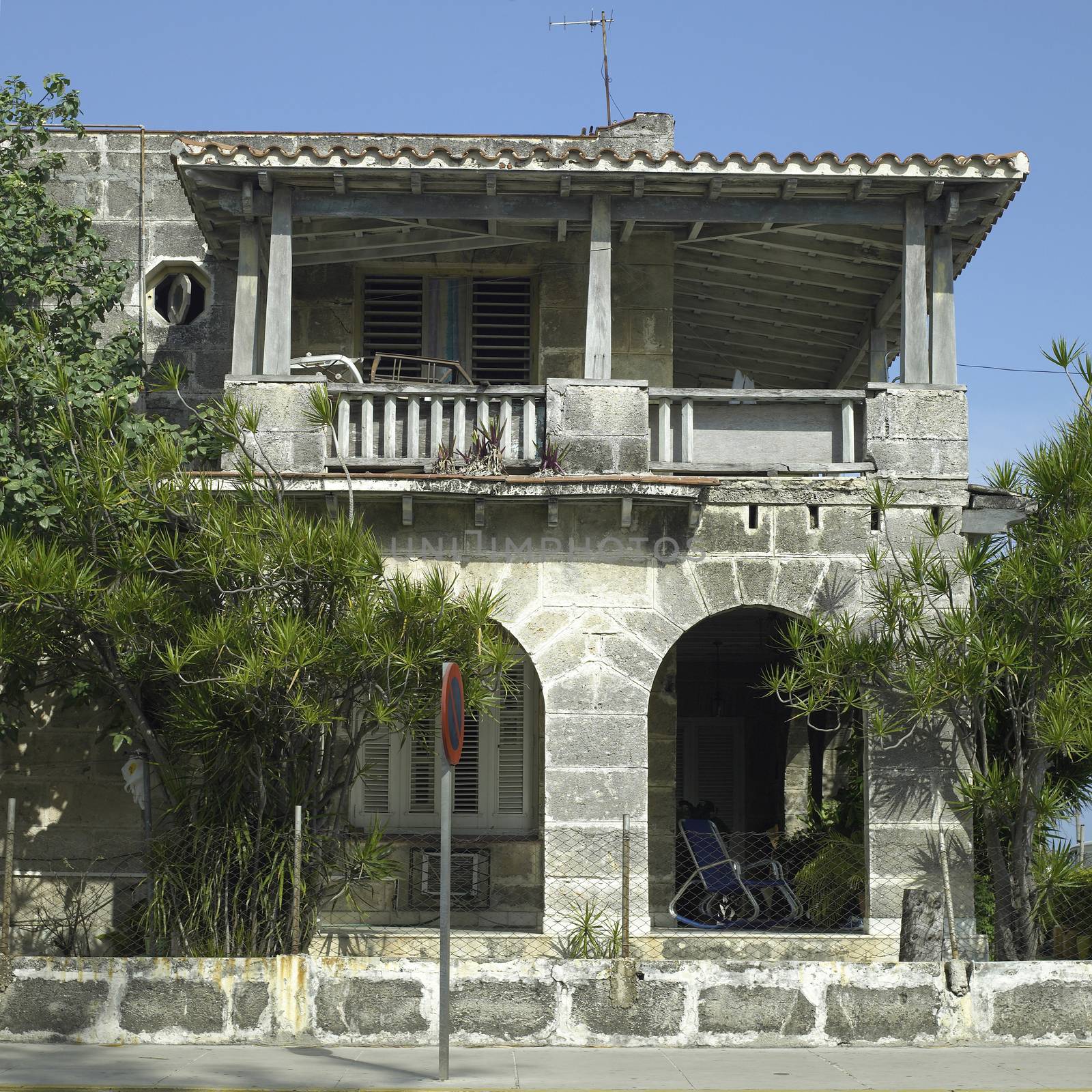 Main and upper floors of the fron of a mosedt stone house in the tropics