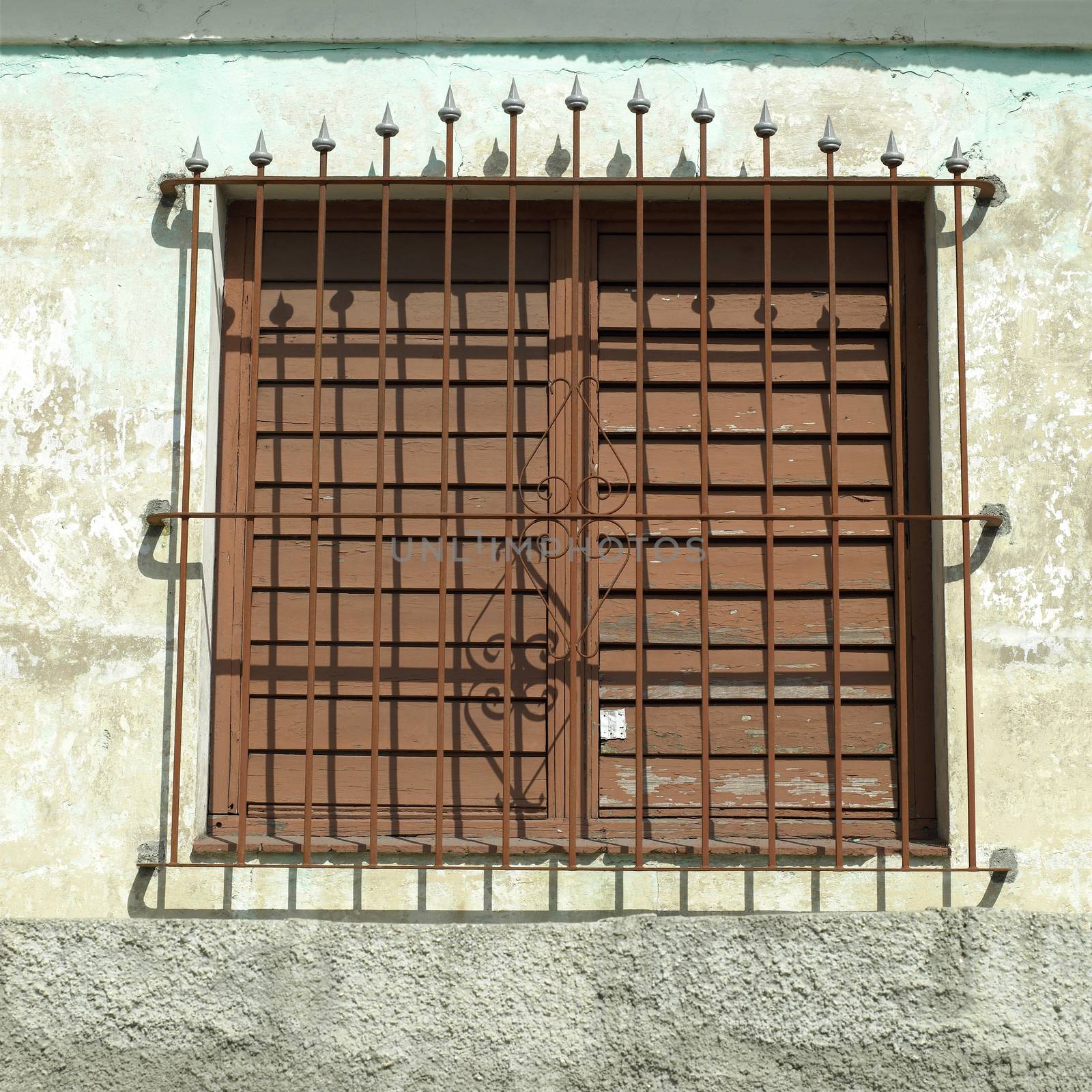 Steel bars and closed shutters of a protected window in a tropical building