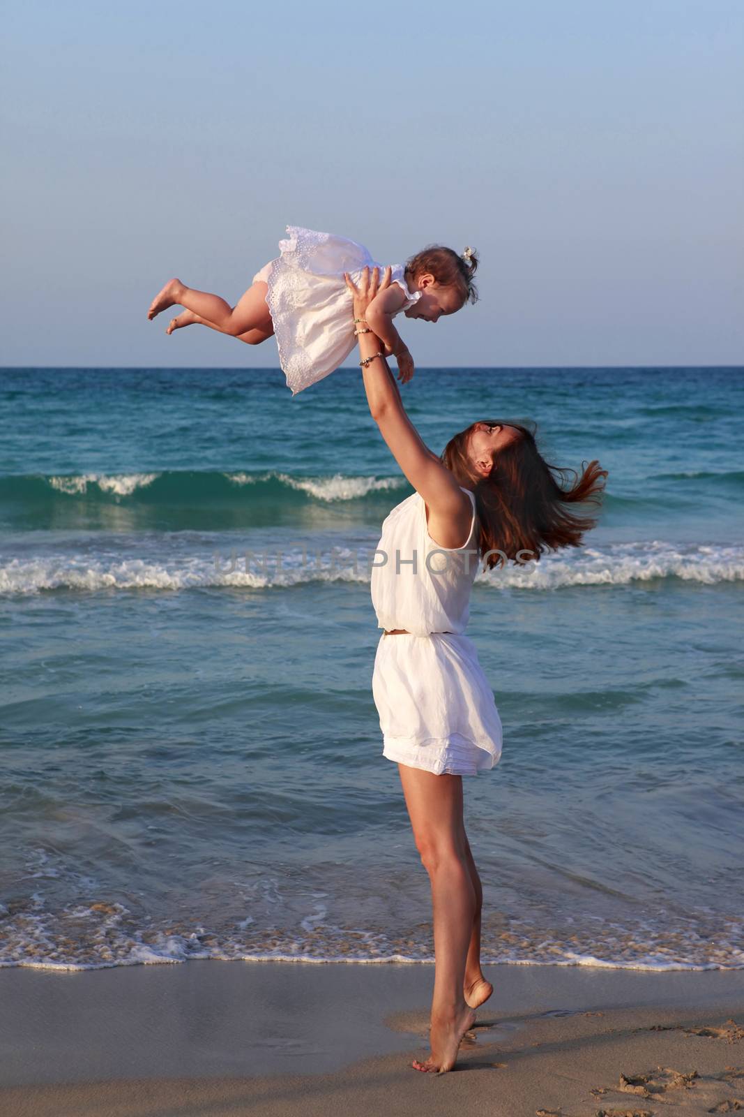 Happy mother holding her daughter on the beach