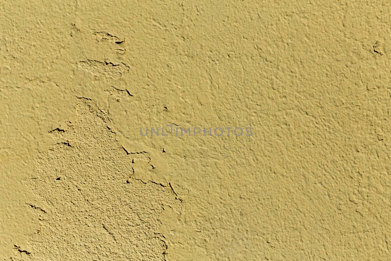A grained yellow concrete wall with texture, some of the parts are falling of