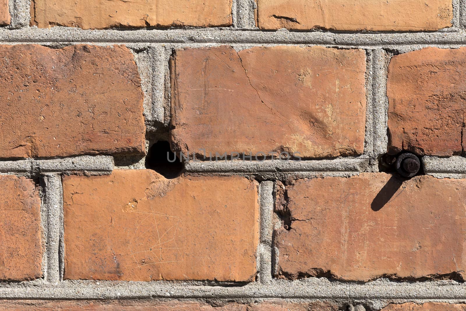 A detailed photo of a brick wall with all the damaged parts and the plaster. This one also have a hole and a bolt sticking out