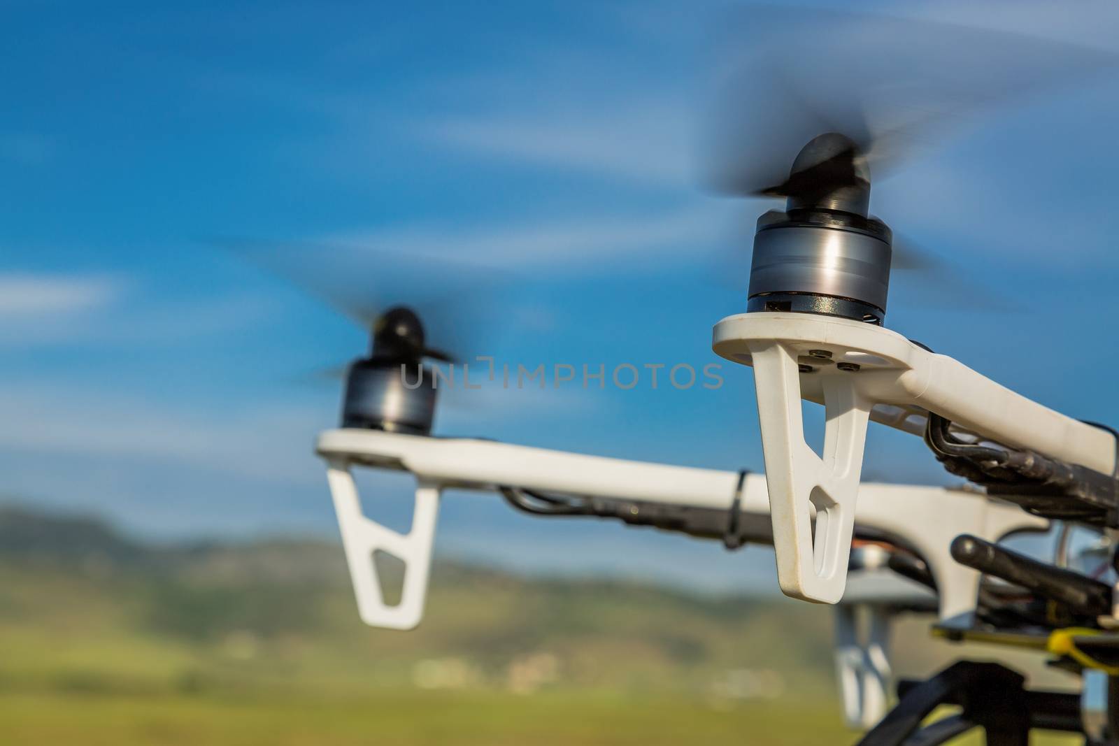 blurred spinning propellers of a hexacopter drone flying over rolling  prairie