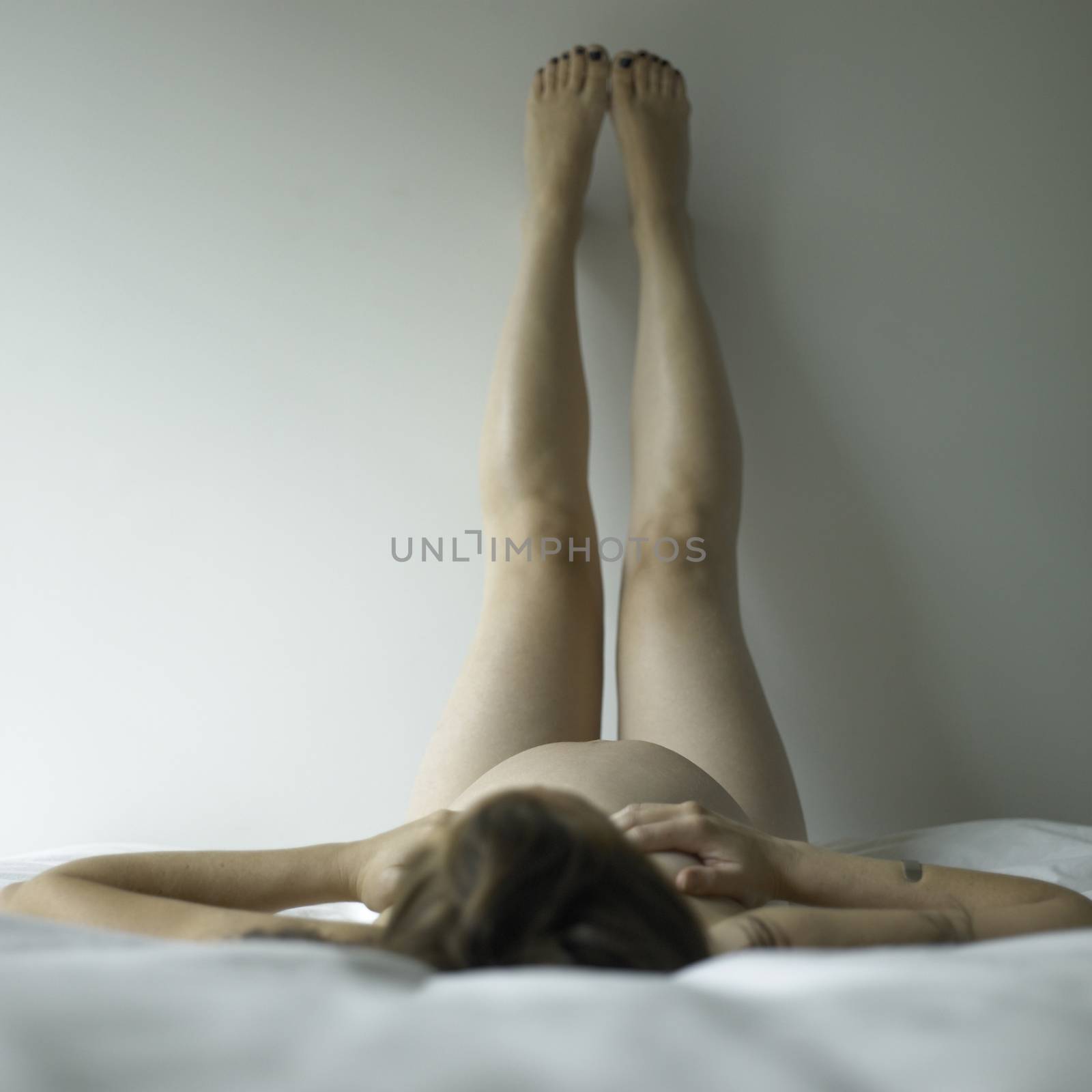 Naked pregnant woman lying on her back with legs up