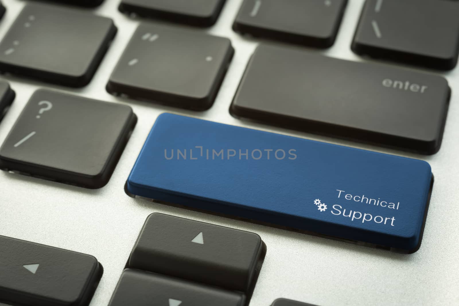 Close up computer keyboard focus on a blue button with typographic word TECHNICAL SUPPORT and gear sign. Customer service and internet technology concepts.