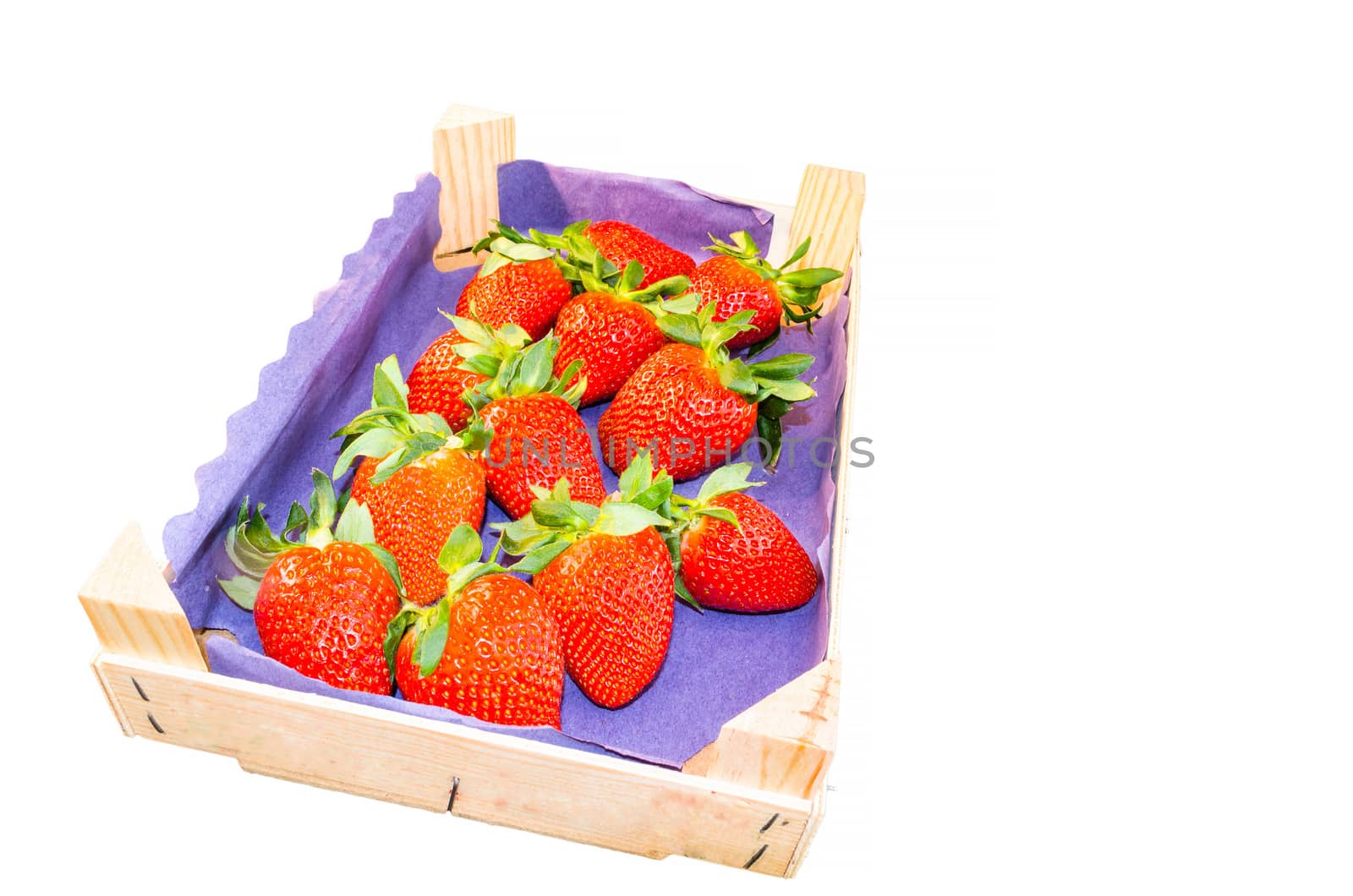 Fresh strawberries against white background in a wooden transport box.