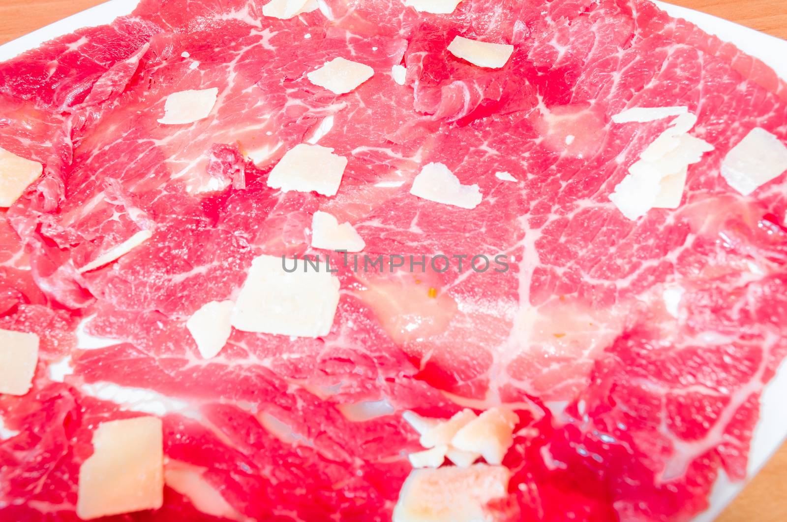 White dish with carpaccio of beef with parmesan.
