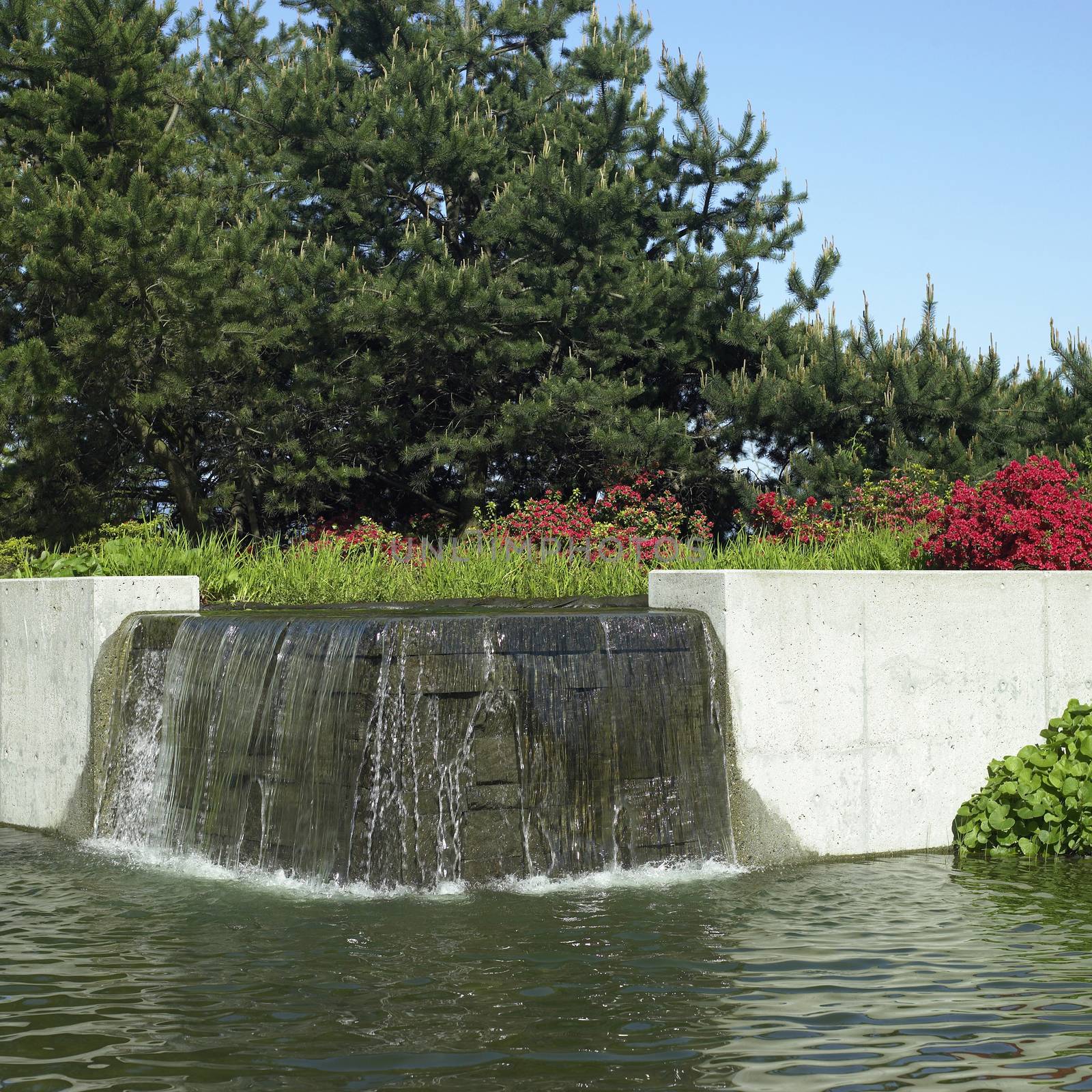 Water feature flows over brick wall in an urban park