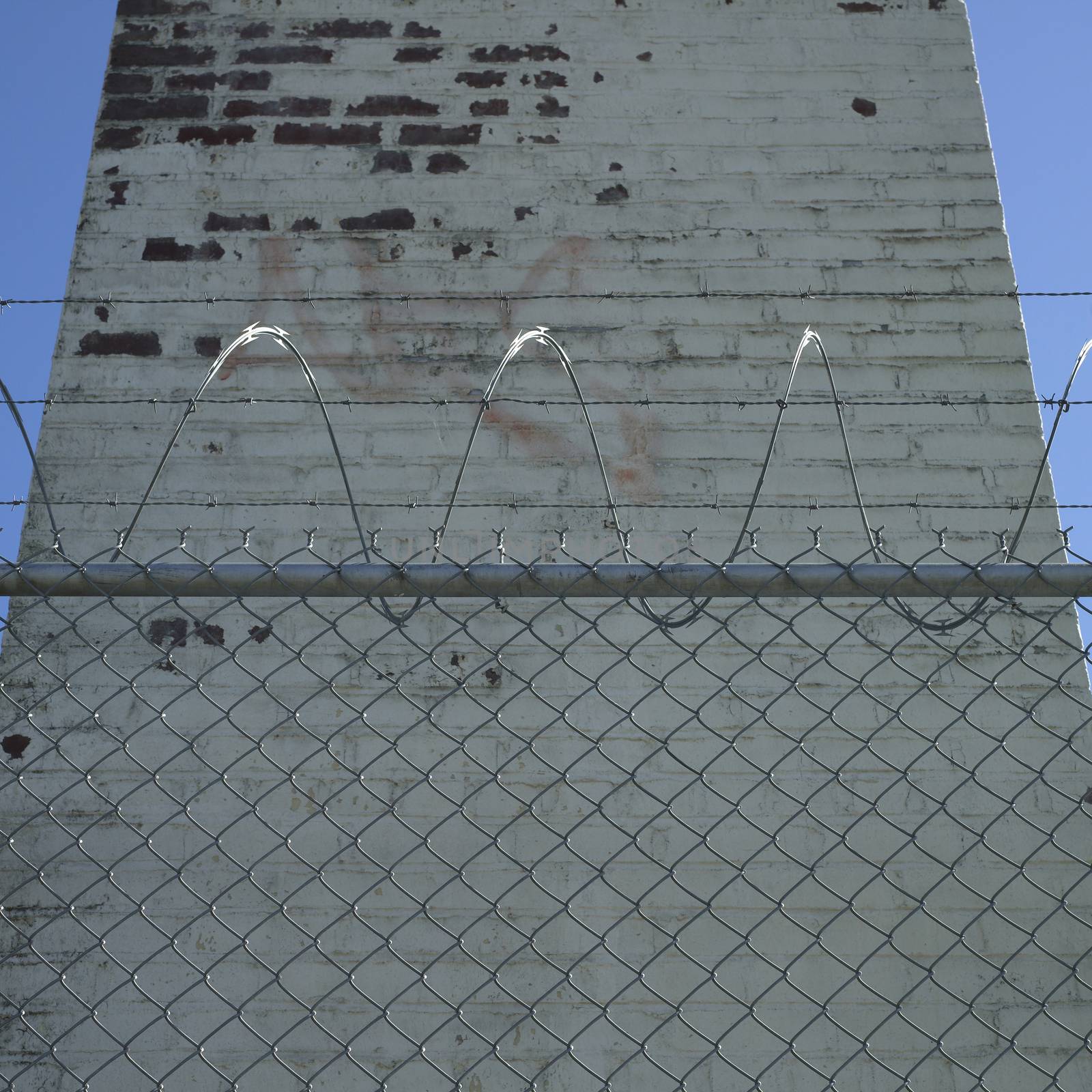 Tall brick chimney behind barbed wire fence