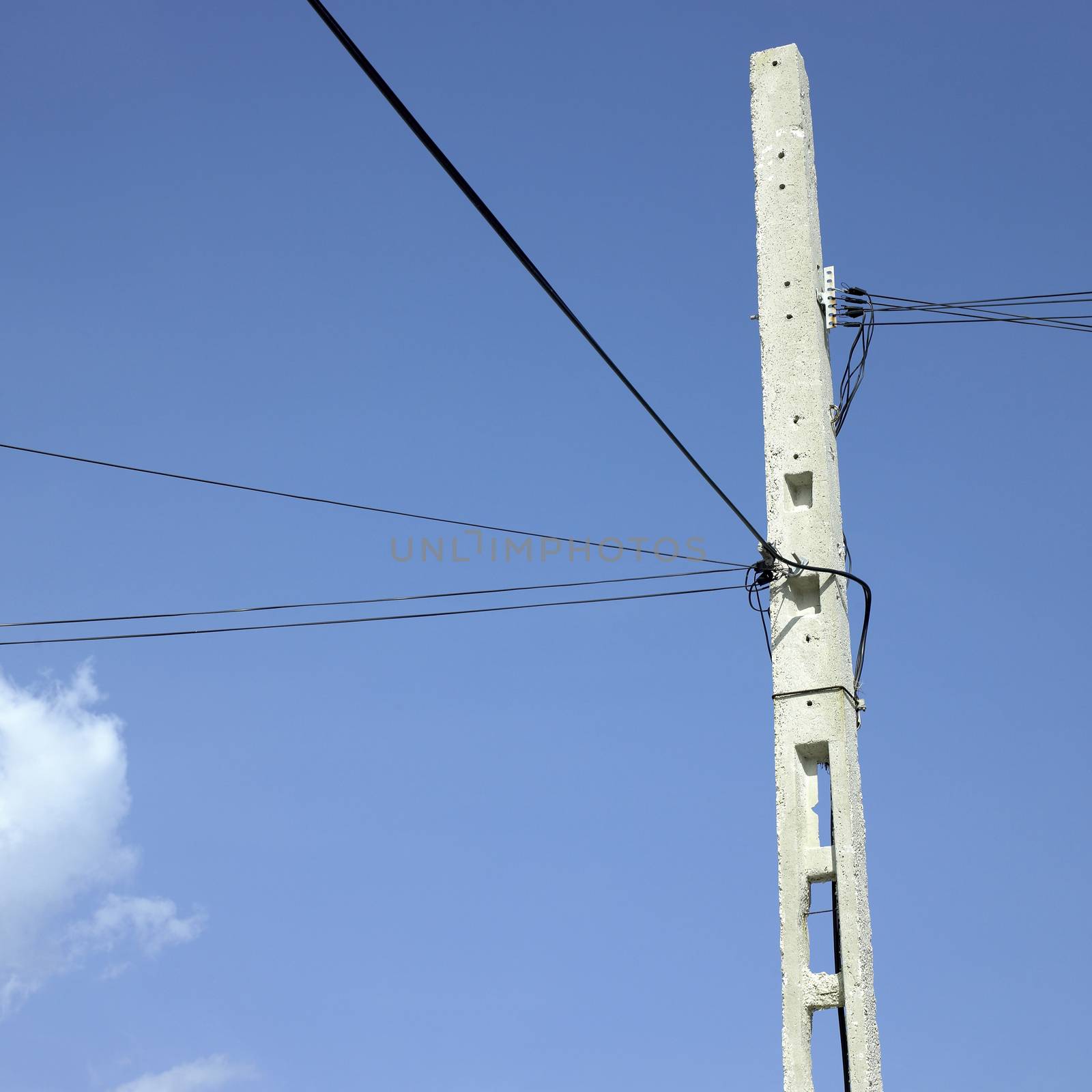 Concrete telephone pole with electrical wires against a blue sky