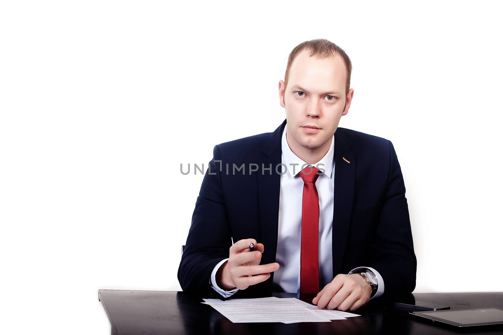 Businessman in red tie at the table gives a pen to sign the contract. Isolated on white background