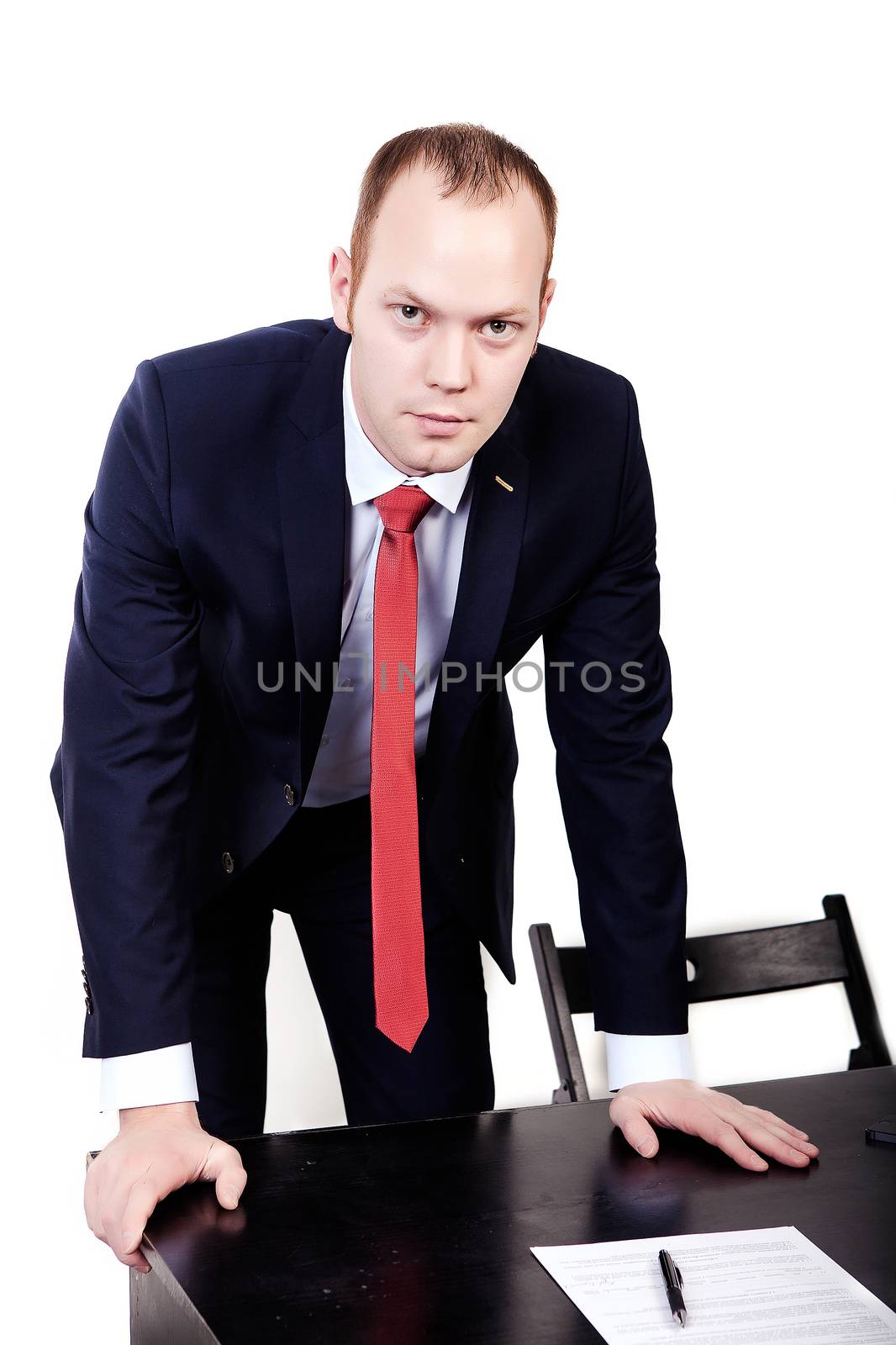Director with a red tie leaned on the table with both hands on an isolated white background.