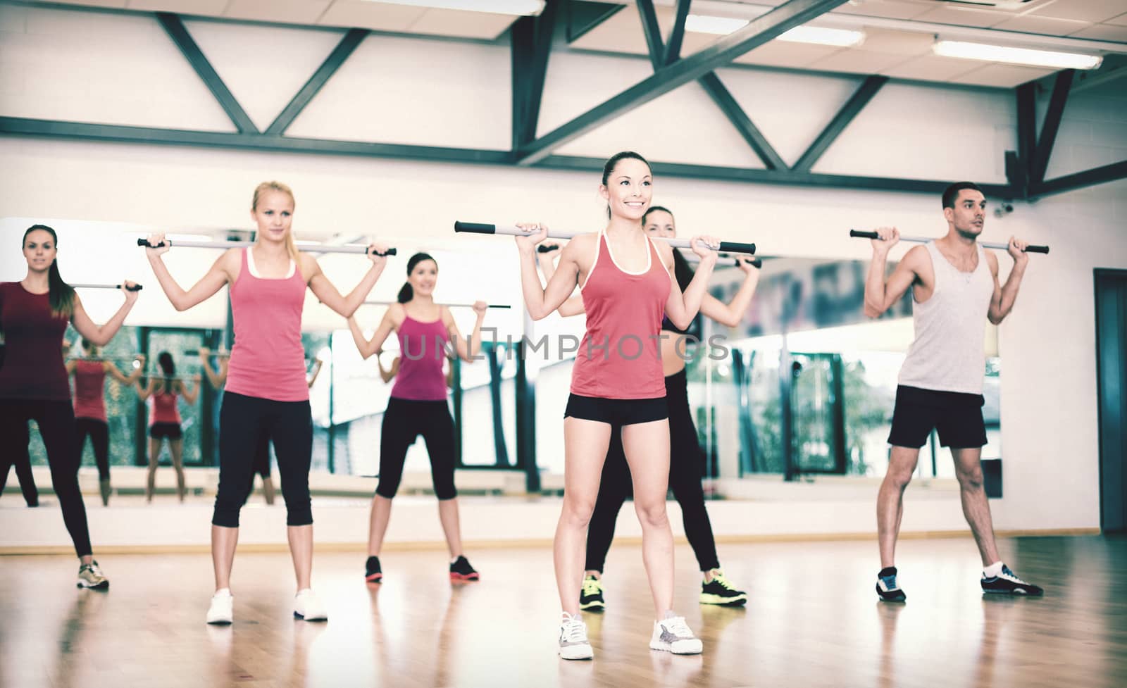 group of smiling people working out with barbells by dolgachov