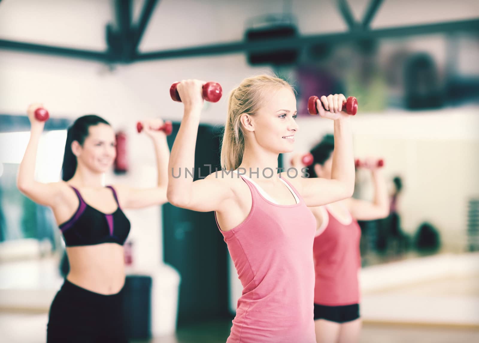 group of smiling women working out with dumbbells by dolgachov