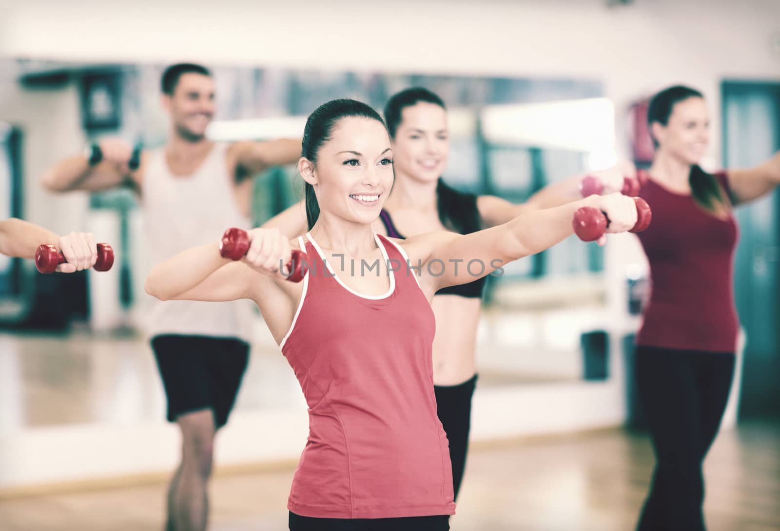 fitness, sport, training, gym and lifestyle concept - group of smiling people working out with dumbbells in the gym