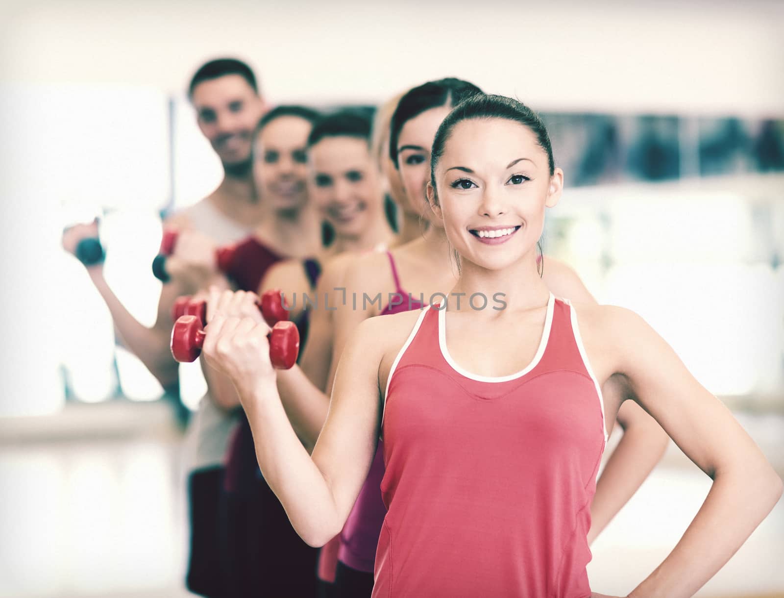 fitness, sport, training, gym and lifestyle concept - group of smiling people lifting dumbbells in the gym