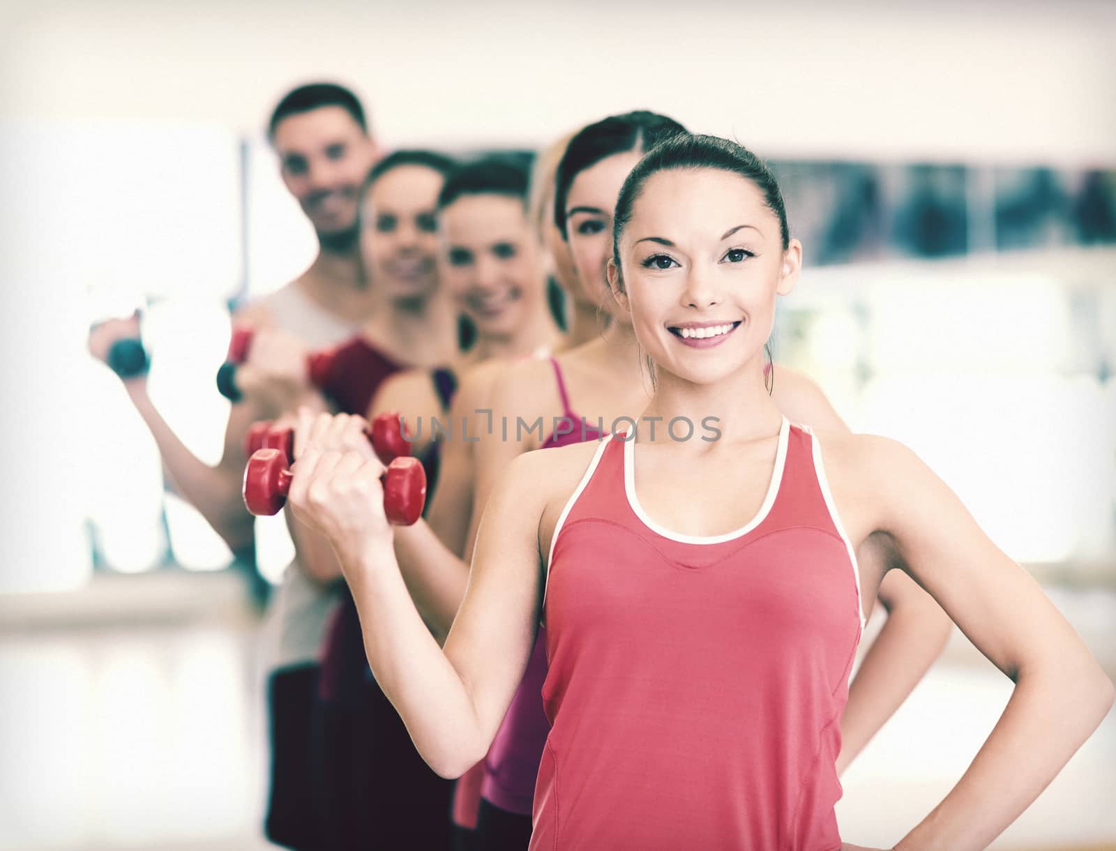 group of smiling people with dumbbells in the gym by dolgachov