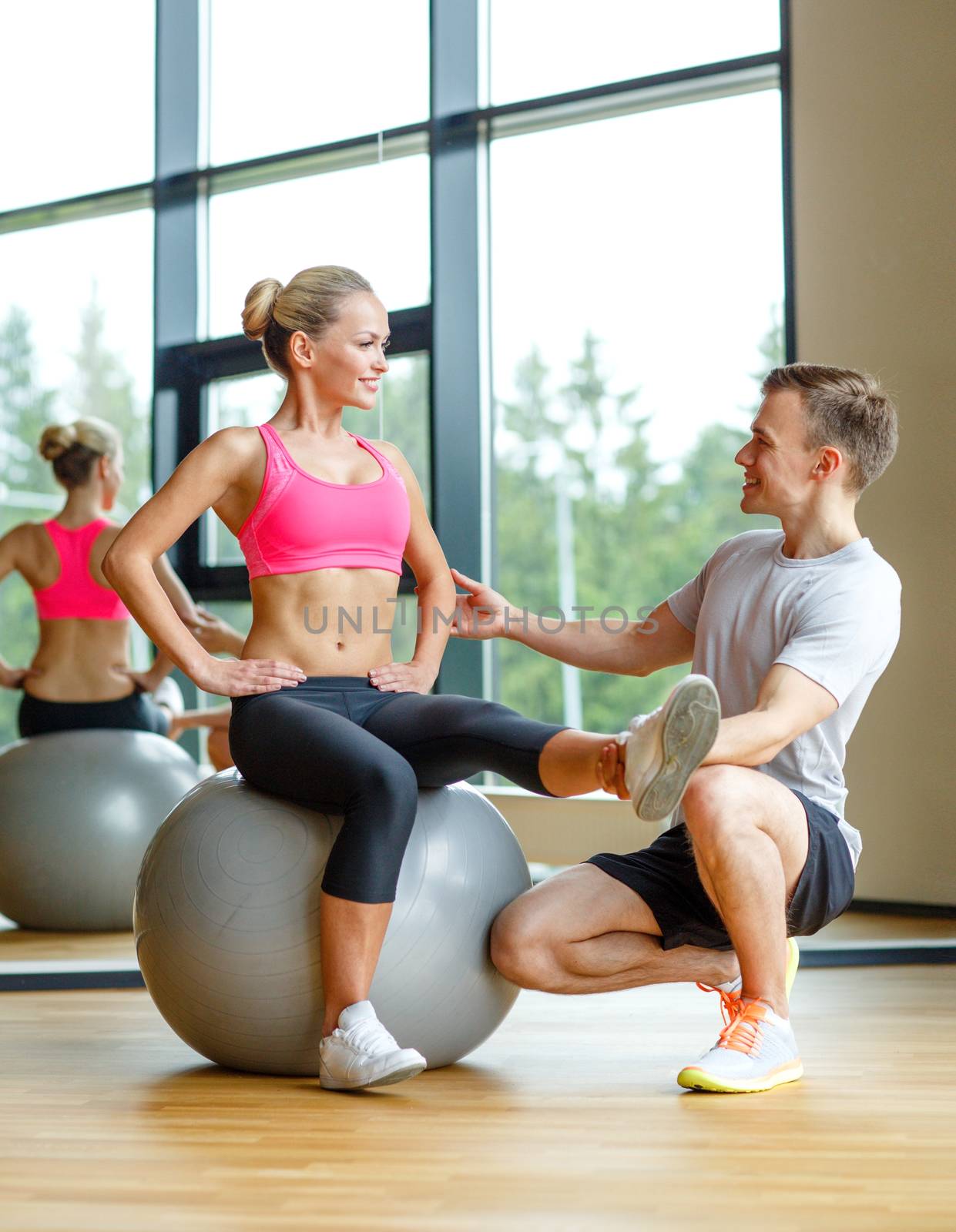 smiling man and woman with exercise ball in gym by dolgachov