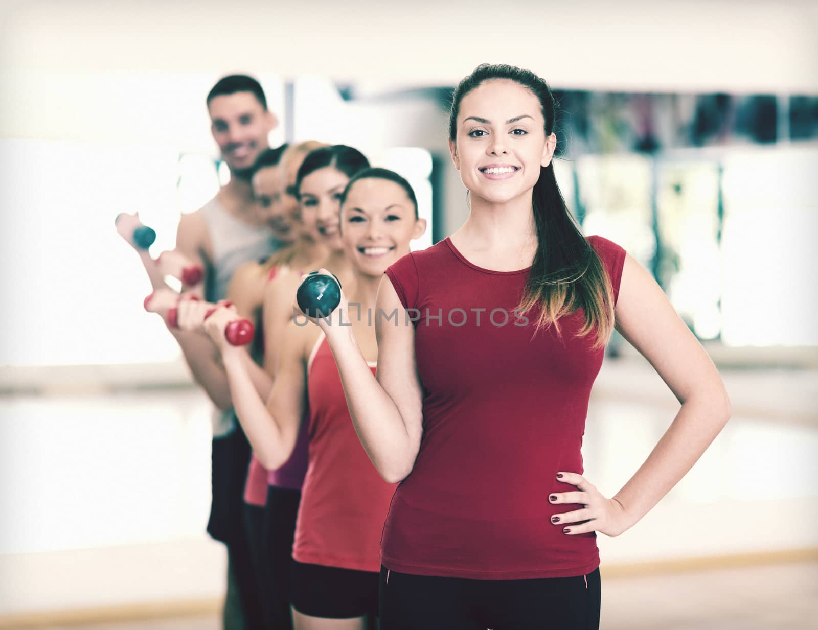 group of smiling people with dumbbells in the gym by dolgachov