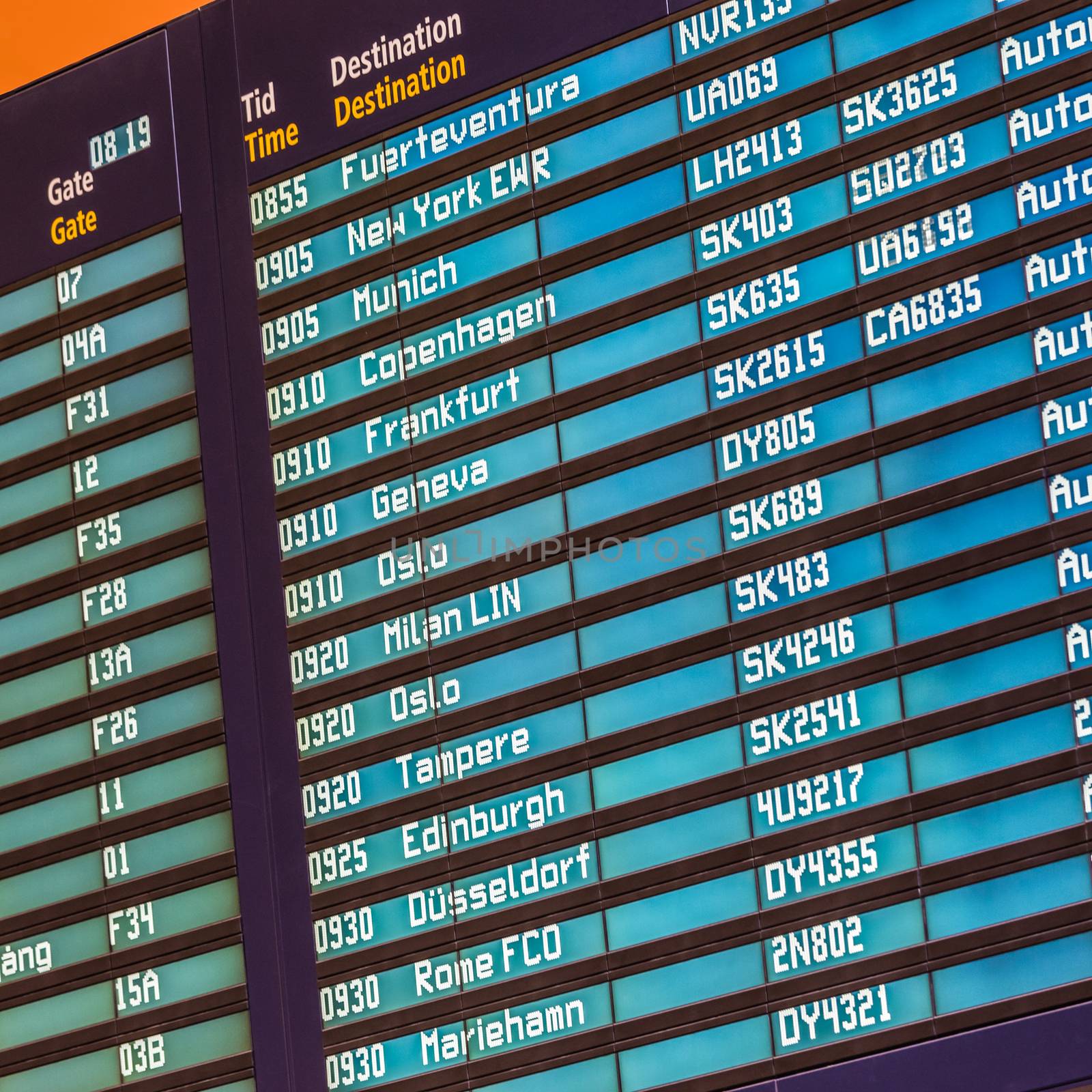 Departures board at the airport terminal hall in front of check in couters. Focus on flight schedule display.