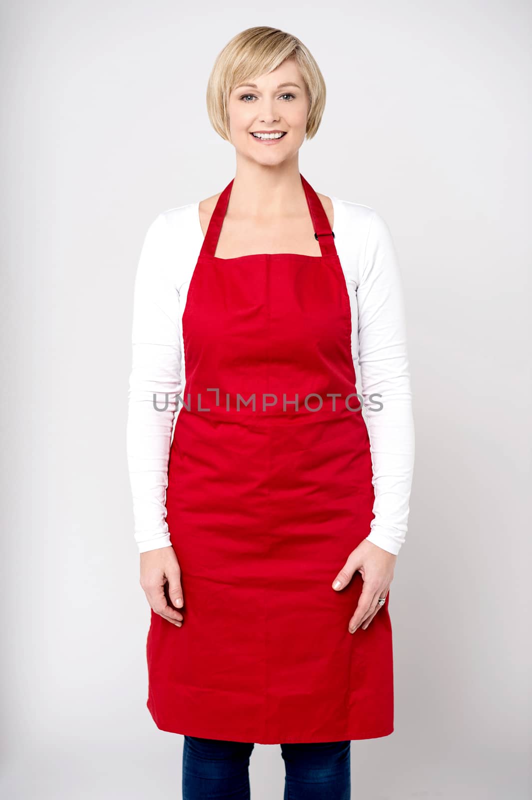 Happy middle aged female chef over grey background.