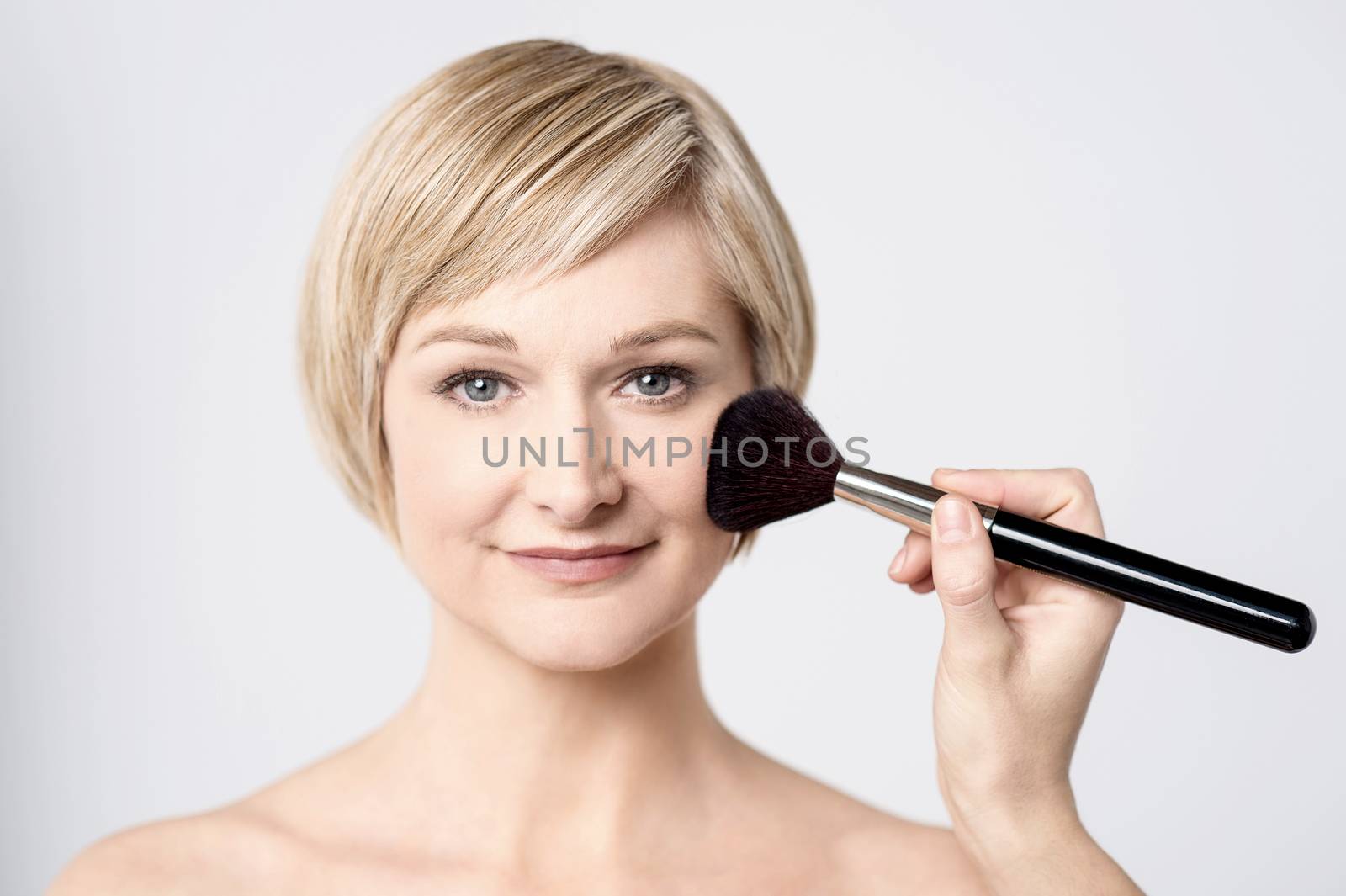 Attractive woman using makeup brush by stockyimages