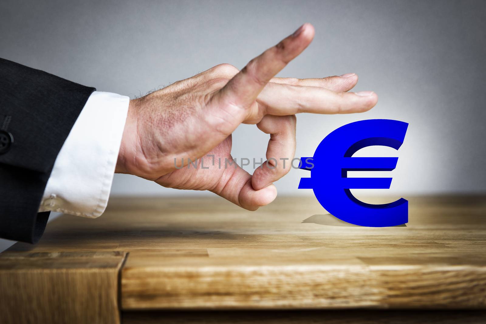 Business Man shoots with his finger off the Euro sign of a table