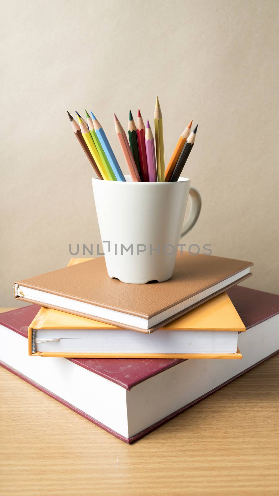 stack of book with color pencil on wood table background