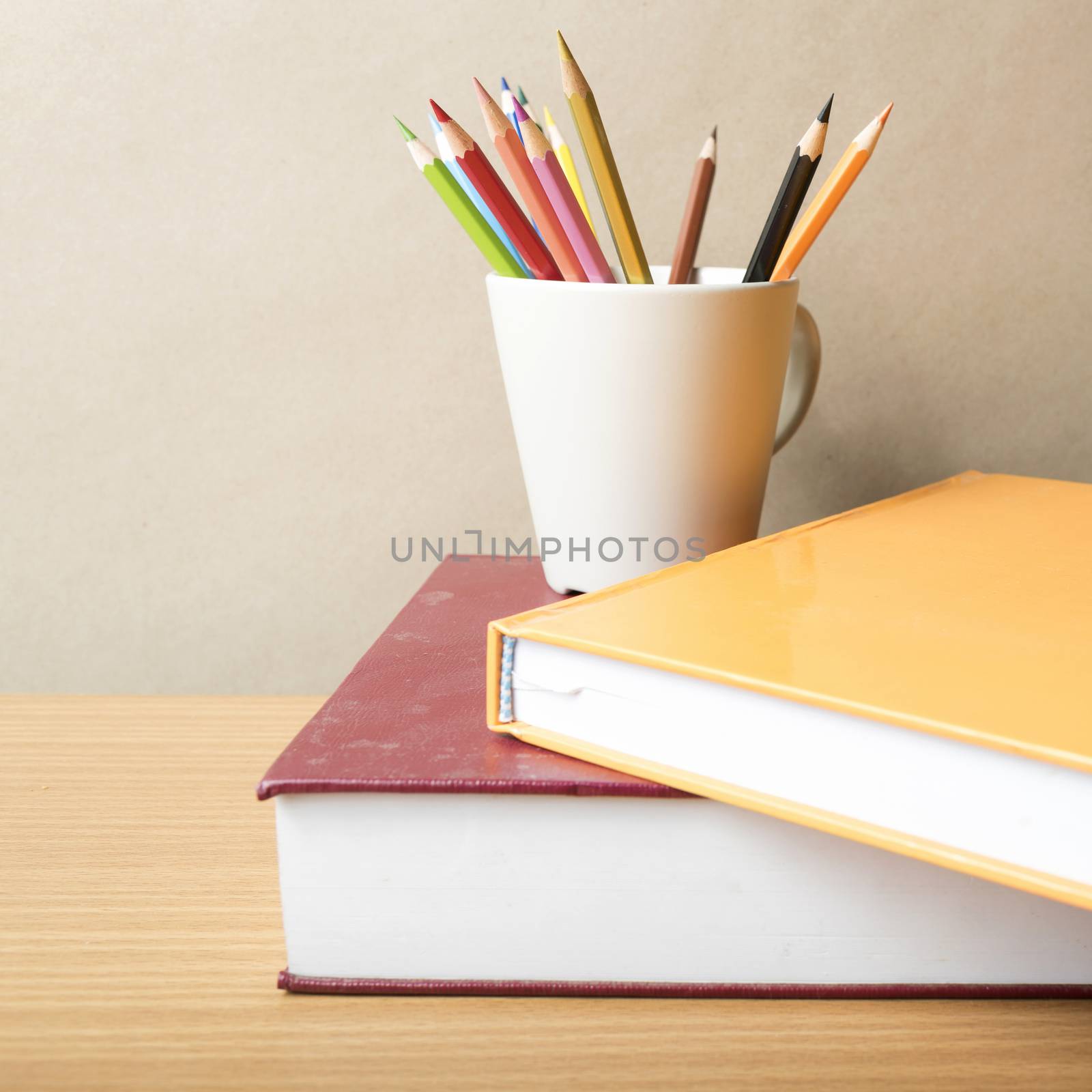 stack of book with color pencil on wood table background