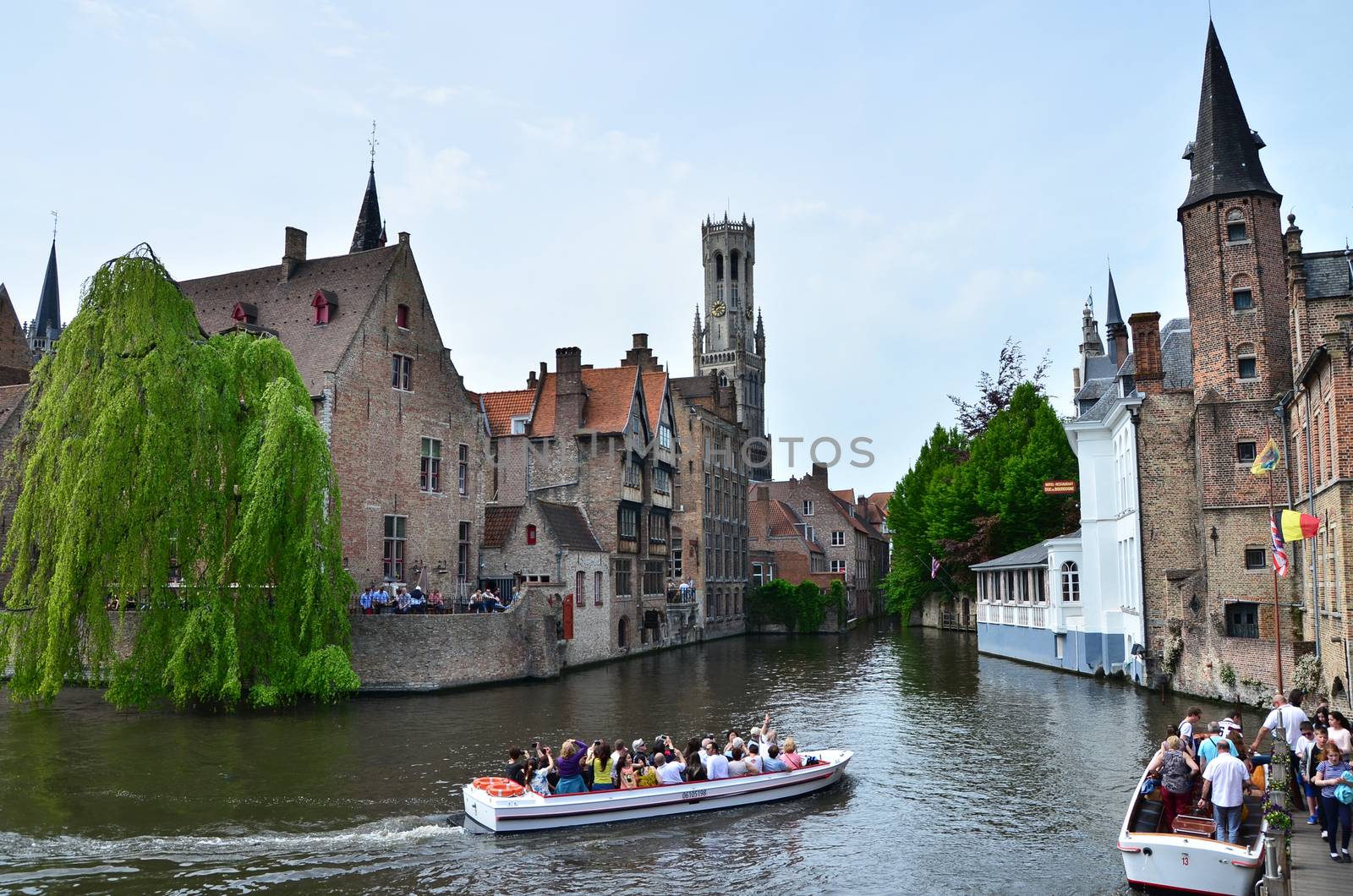 Bruges, Belgium - May 11, 2015: Tourist visit Rozenhoedkaai (The Quai of the Rosary) in Bruges, Belgium. One of Bruges most picturesque locations. With a view of the Bruges Belfry in the distance.